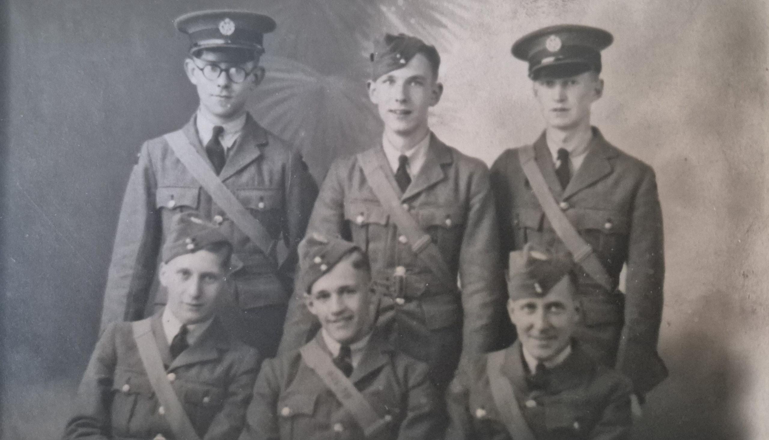 A black and white picture of six young servicemen, with three of them standing behind the three who are sitting down.