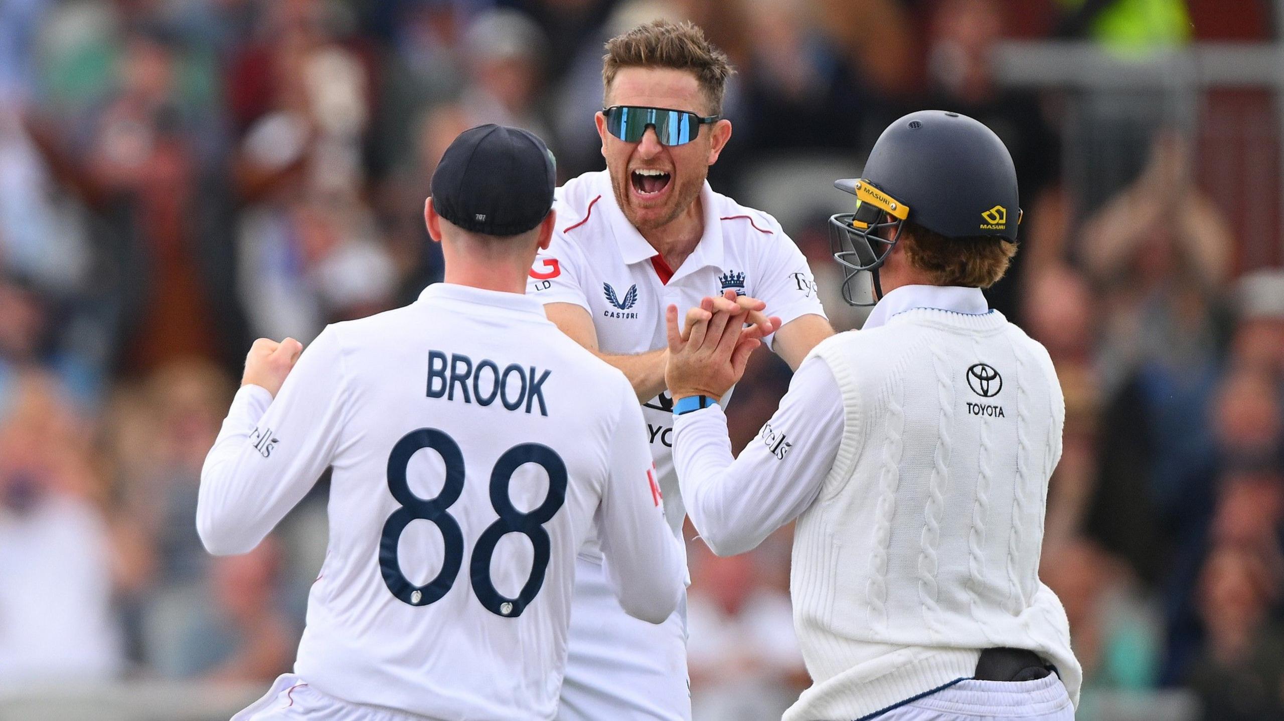 Liam Dawson, wearing sunglasses, celebrates a wicket with Harry Brook and Ollie Pope, who is wearing a helmet