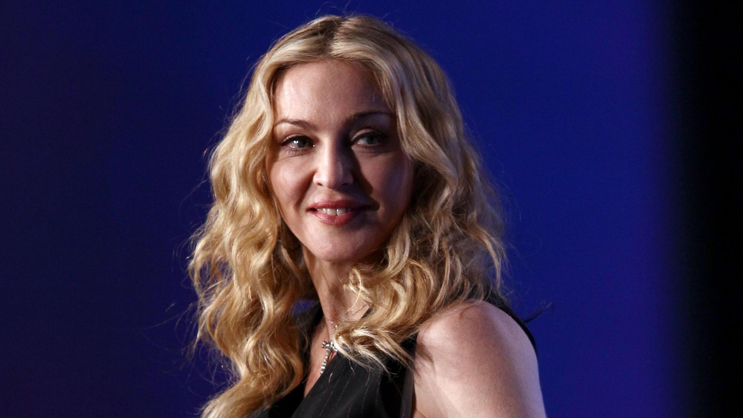 Head and shoulders shot of Madonna with blonde hair and a black top. She is looking slightly away from the camera.