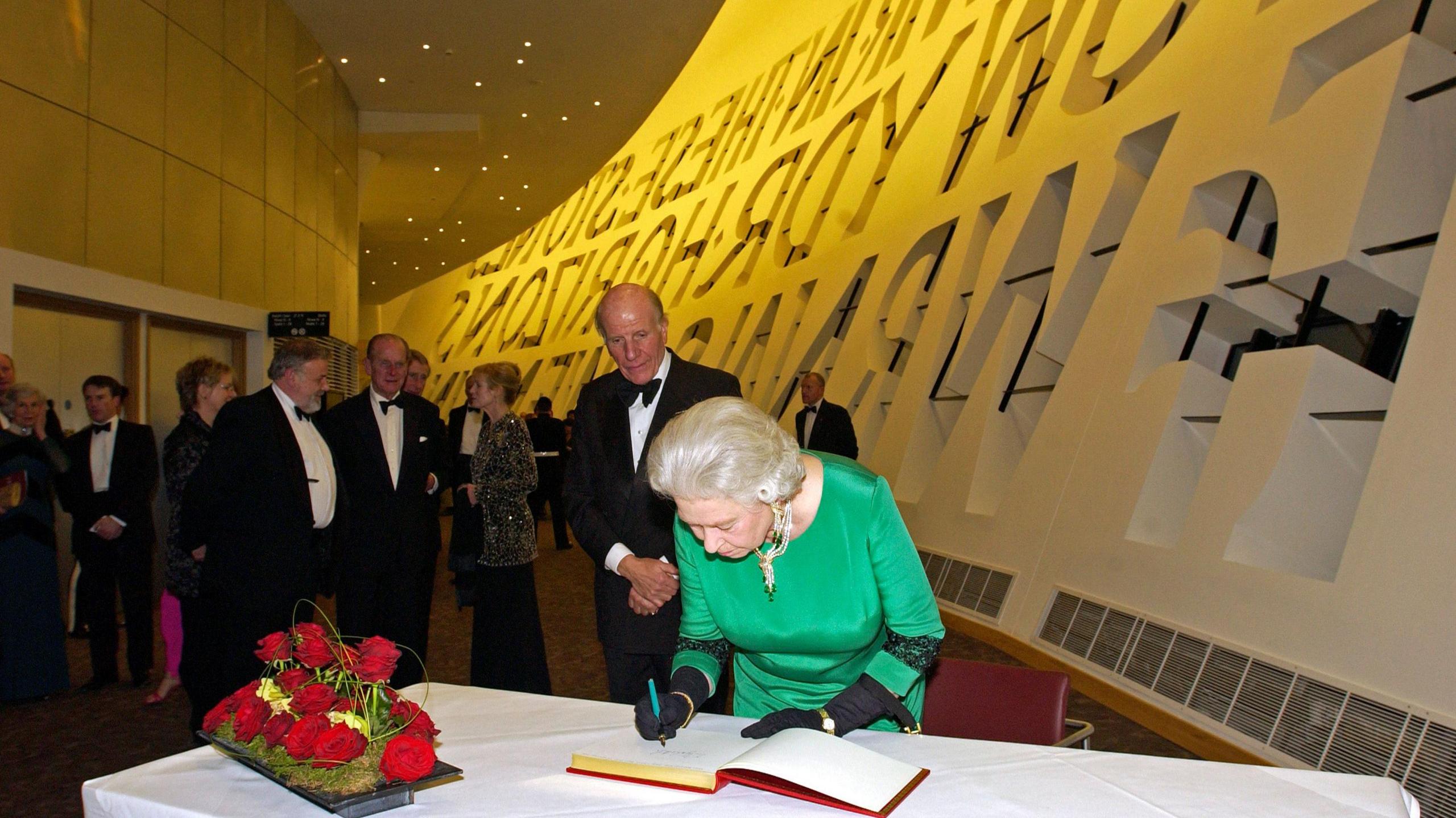 Queen Elizabeth II signs a guest book at the Wales Millennium Centre during its opening celebration on 28 November, 2004.