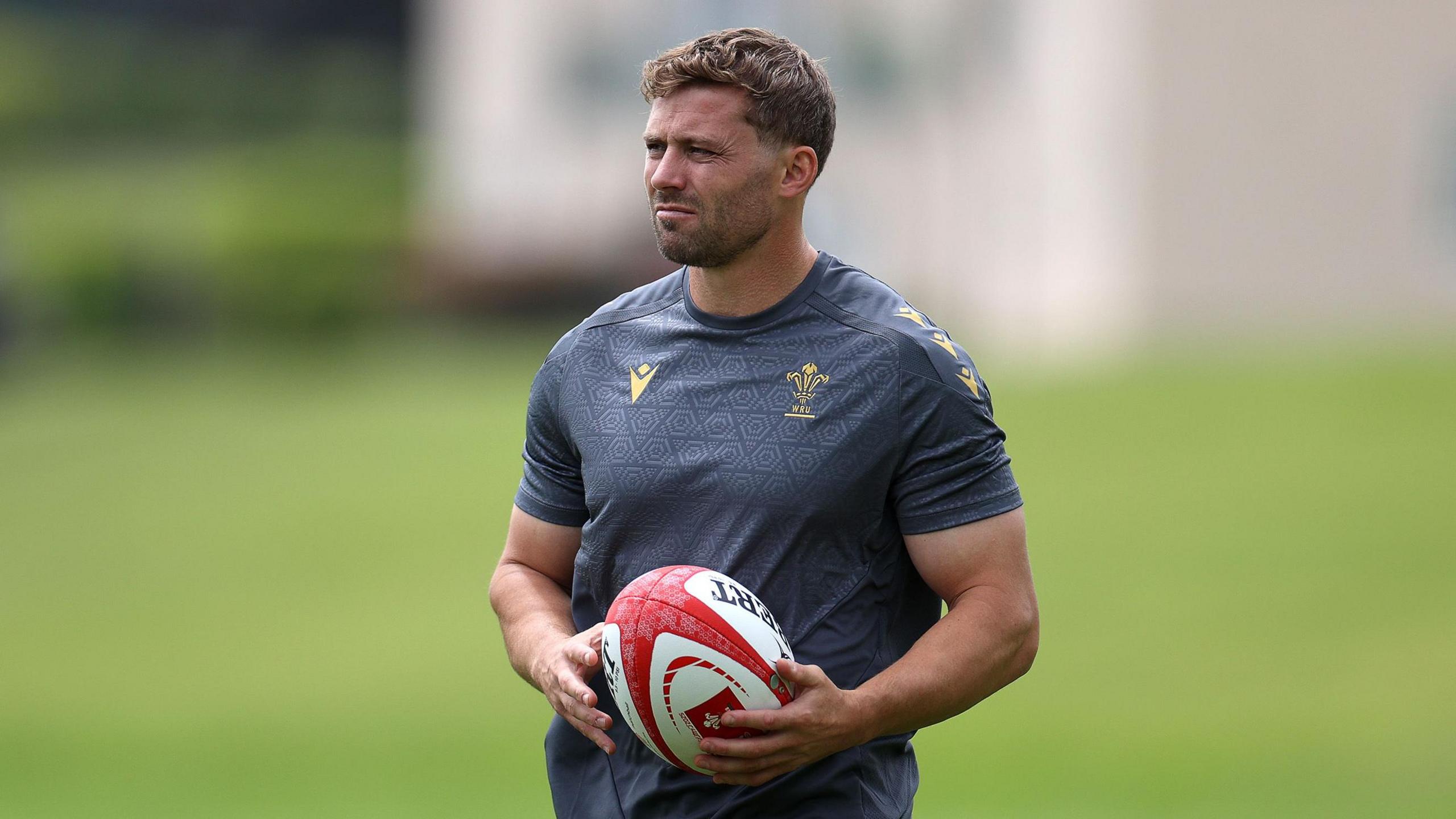 Leigh Halfpenny holds a ball while watching Wales training