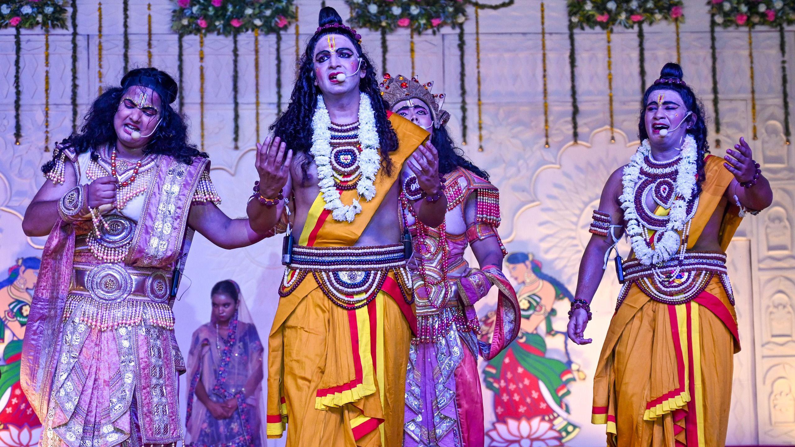 Three men in elaborate costumes depicting Hindu mythological figures, at a Ramlila being staged in Noida, India. 