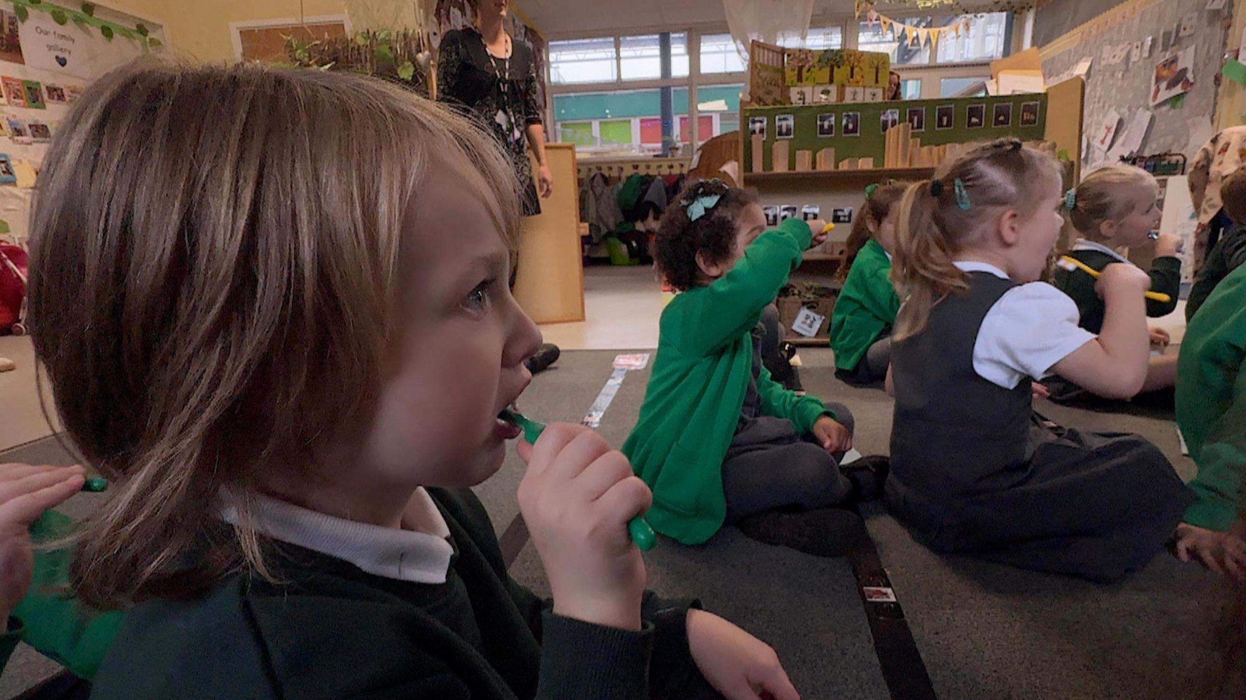 Young children sitting in class and brushing their teeth after lunch.