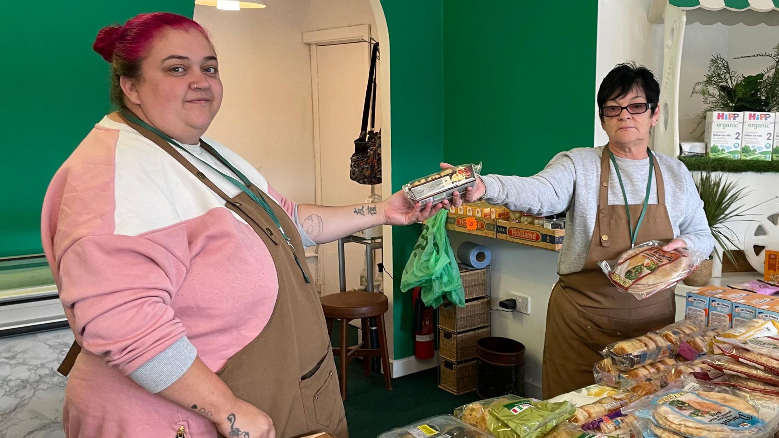 Two of the food bank's volunteers passing food to each other.