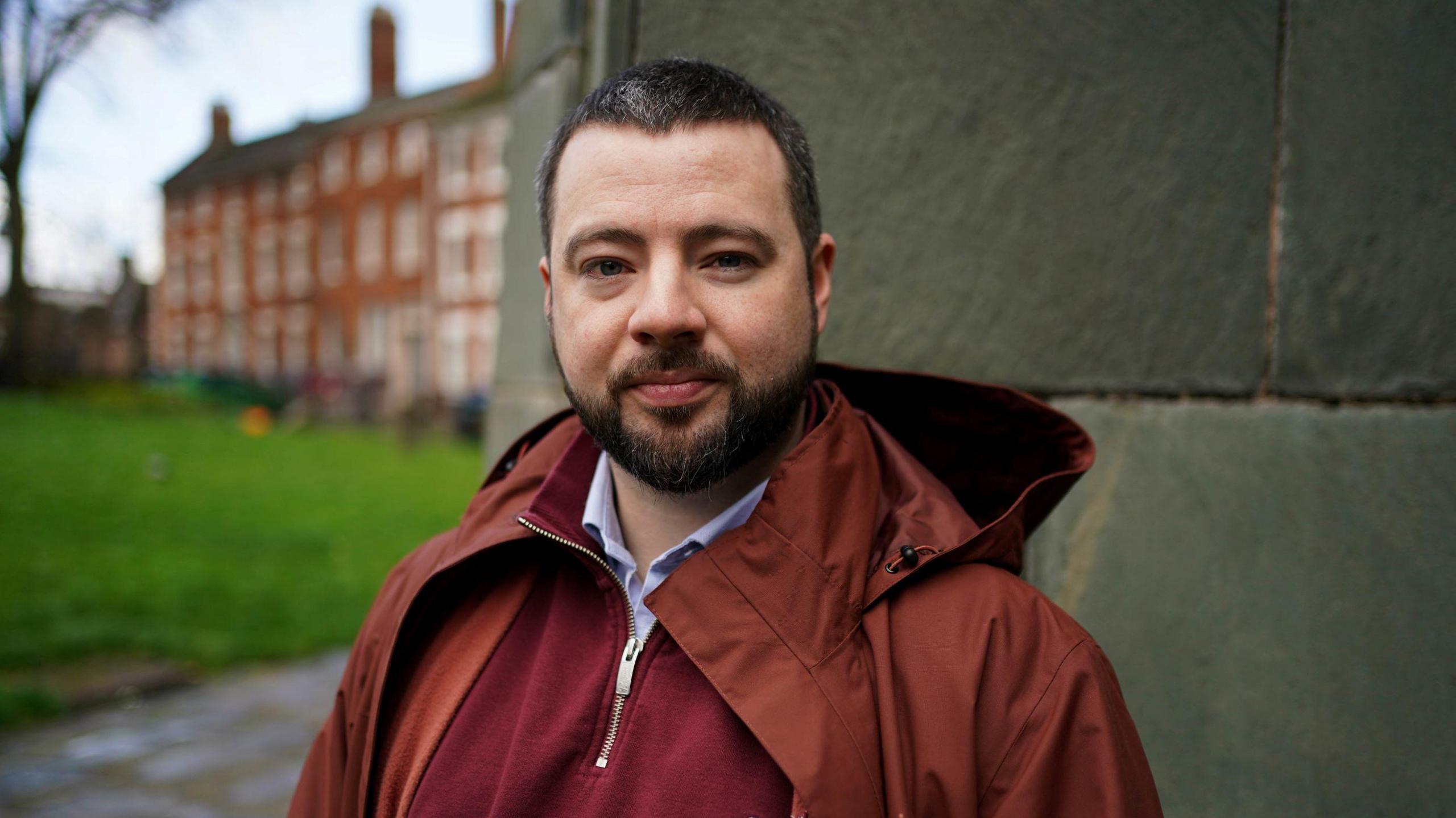 Jason Evans, wearing a maroon jumper and a terracotta coat.