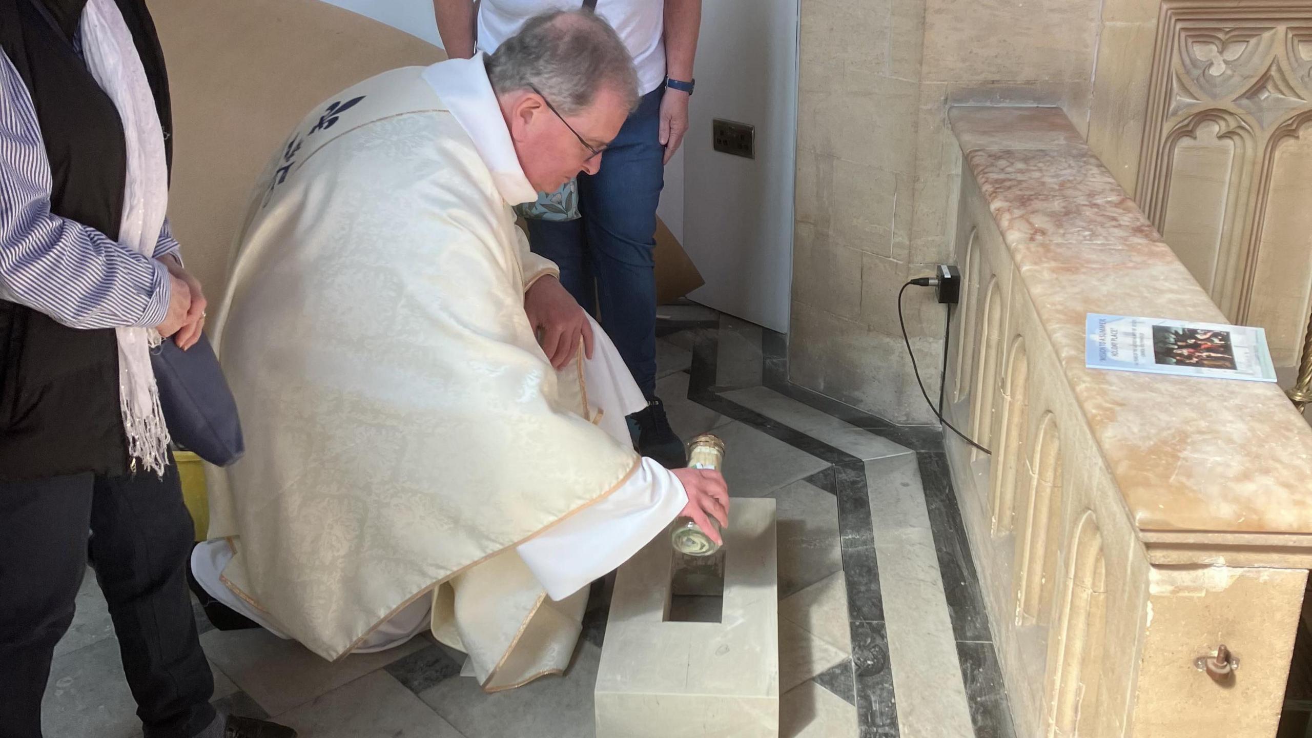 Priest burying time capsule