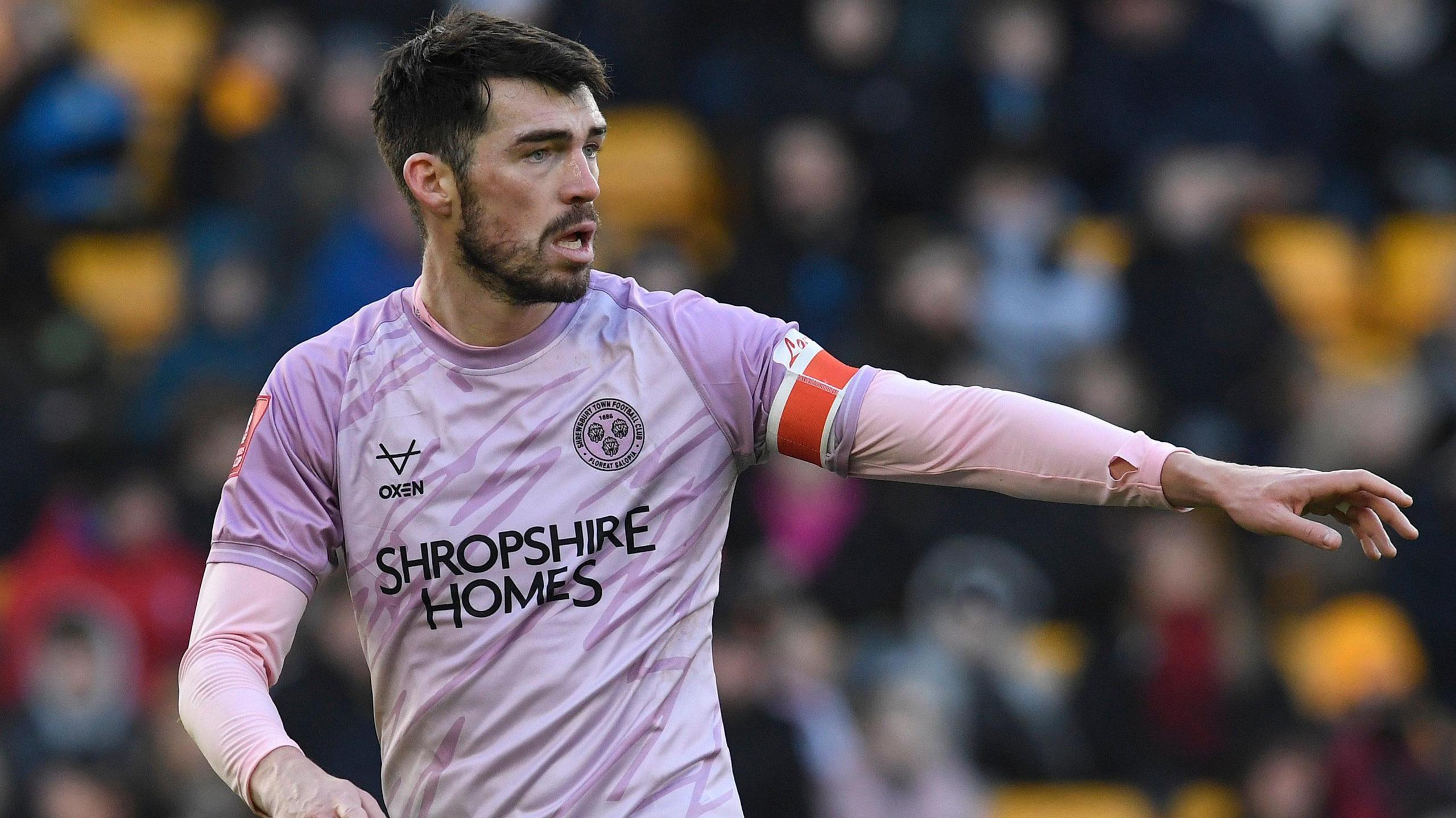 John Marquis in his pink away kit directs his team-mates during a game for Shrewsbury
