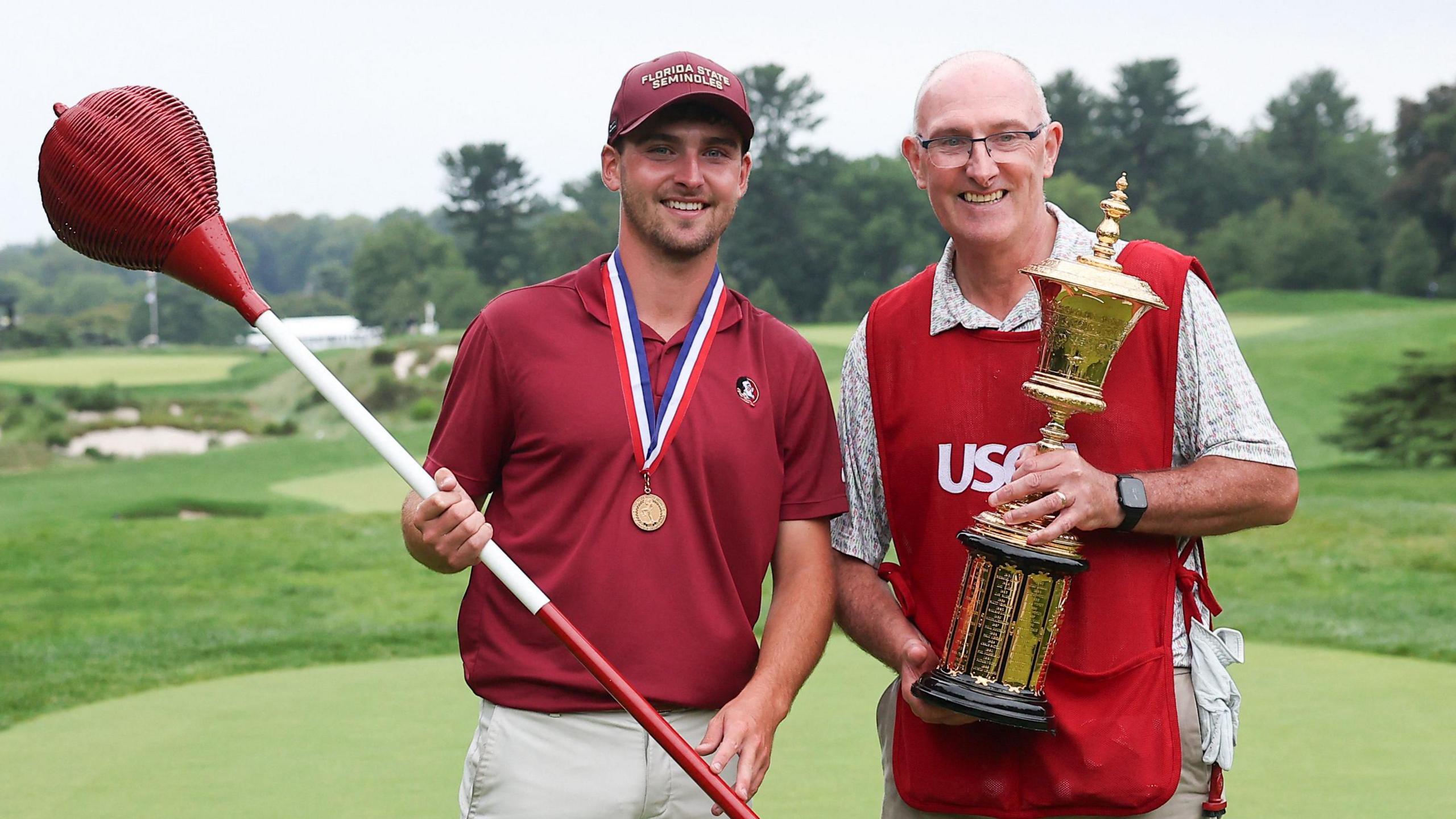 Jack Whaley standing next to his father and caddy Andy, who is holding the US Amateur trophy