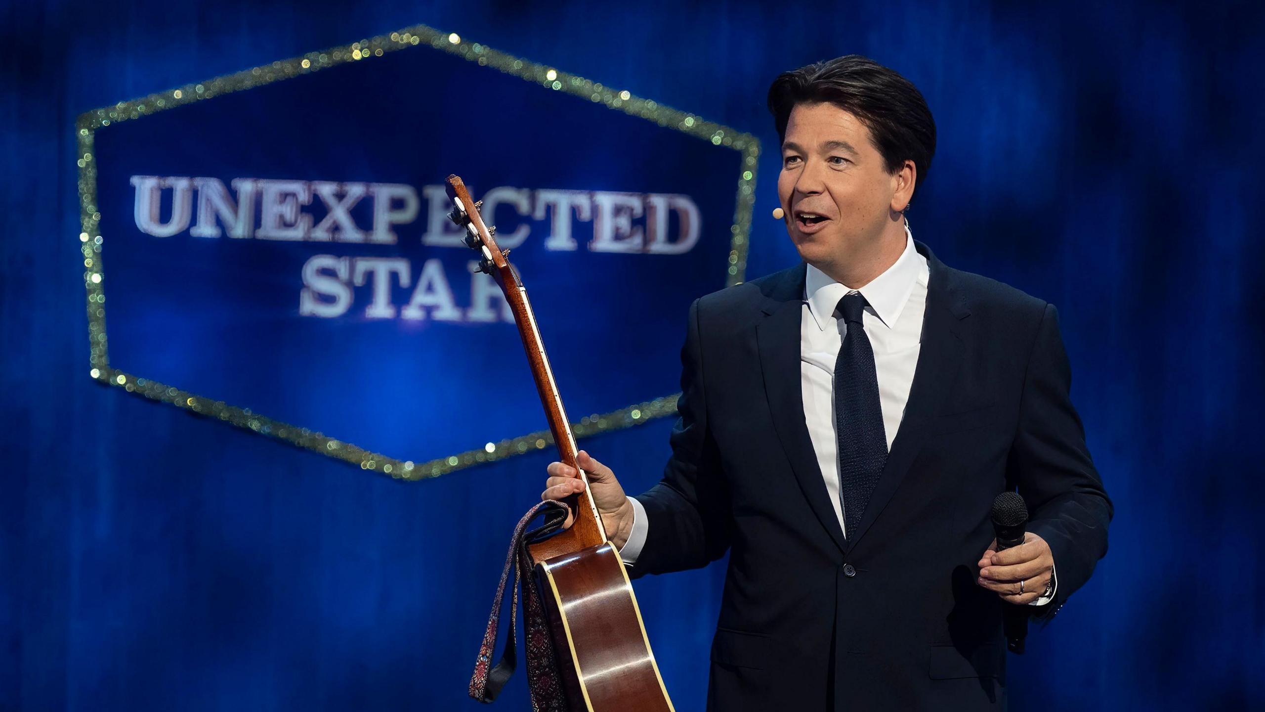 Michael McIntyre holding a guitar while presenting Michael McIntyre's big show