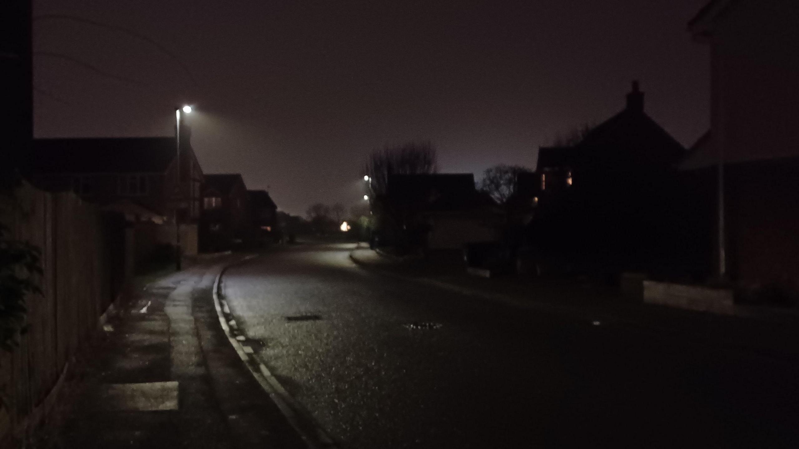 A dark street with very few street lights 