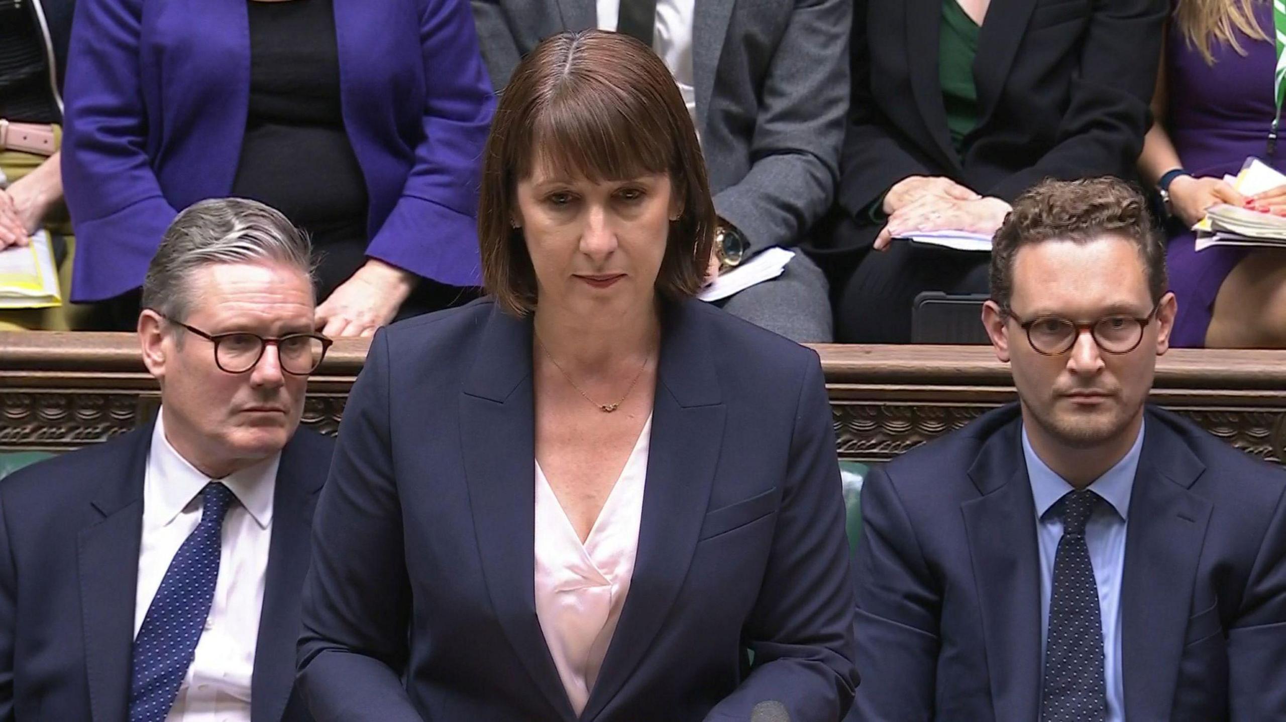 Rachel Reeves speaking in Parliament with Kier Starmer to her right and Darren Jones to her lefy