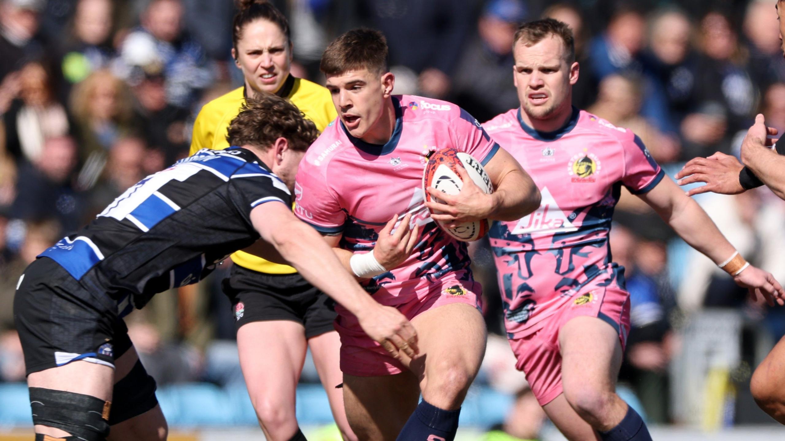 Exeter Chiefs' Joe Hawkins wearing a pink shirt, carrying a rugby ball