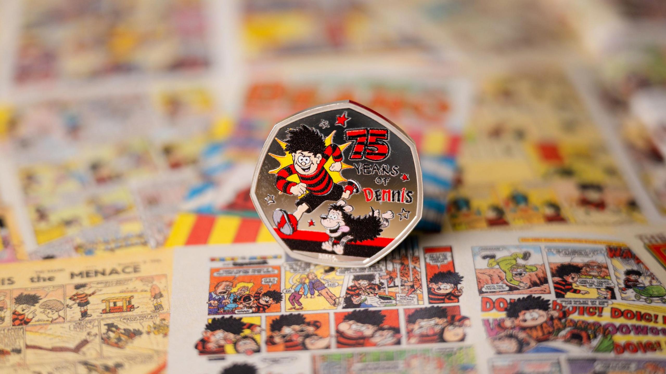 a 50p coin with Dennis the menace and his dog Gnasher, rested on old copies of Beano magazine