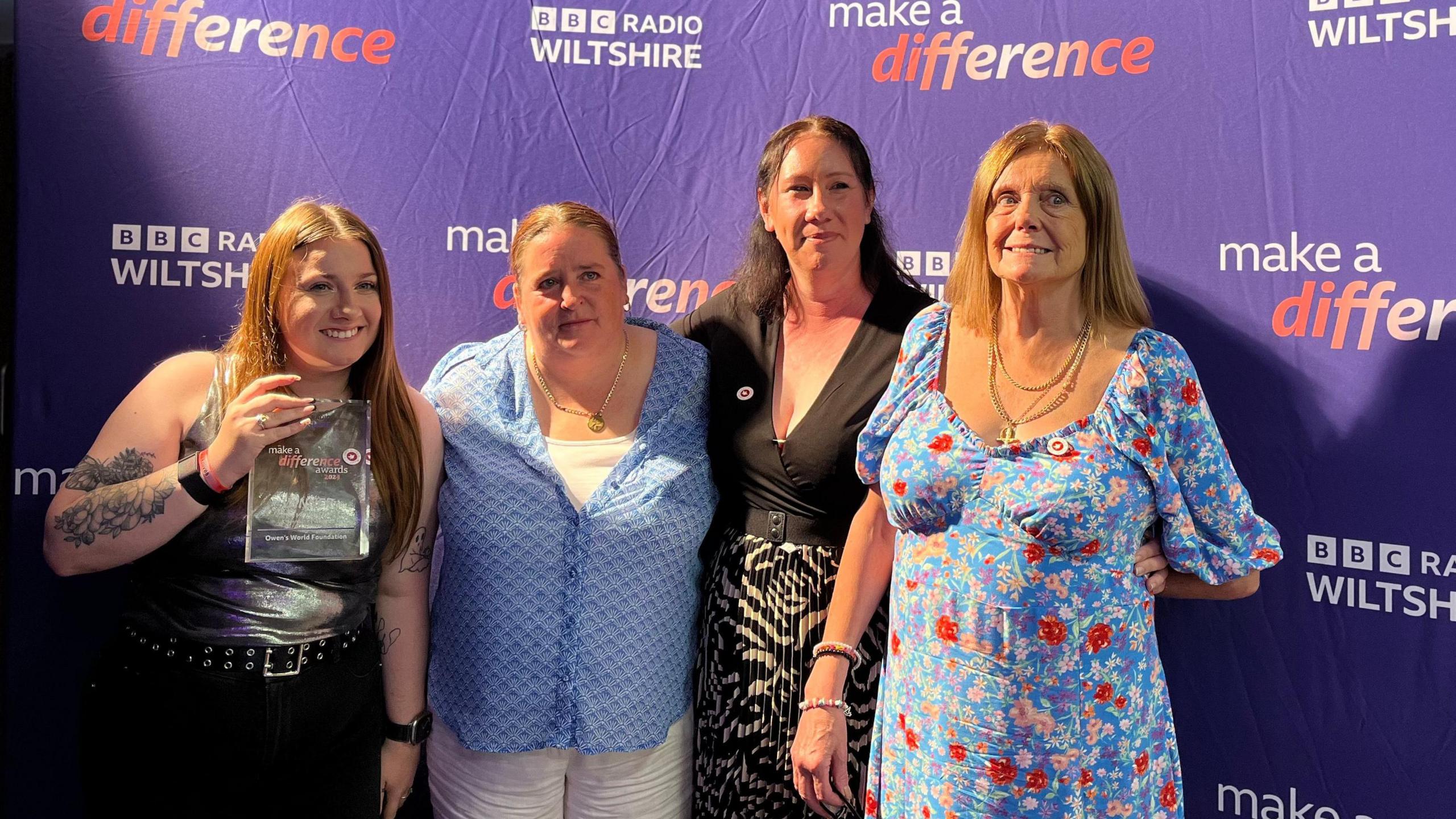 Four women, one holding the award, in front of a BBC Radio Wiltshire banner