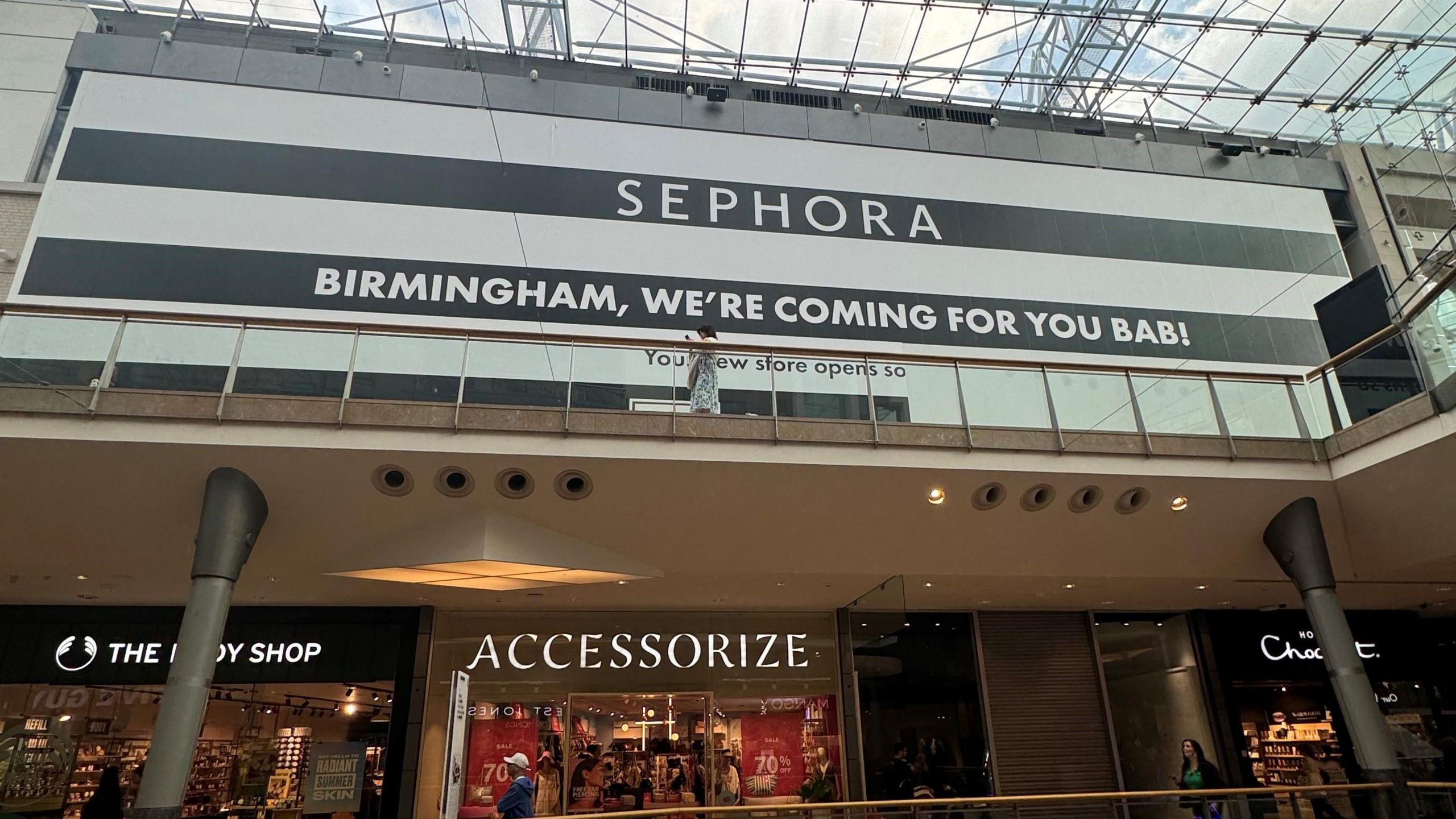 Large black and white boards and signage covers the front of a store in a shopping centre.