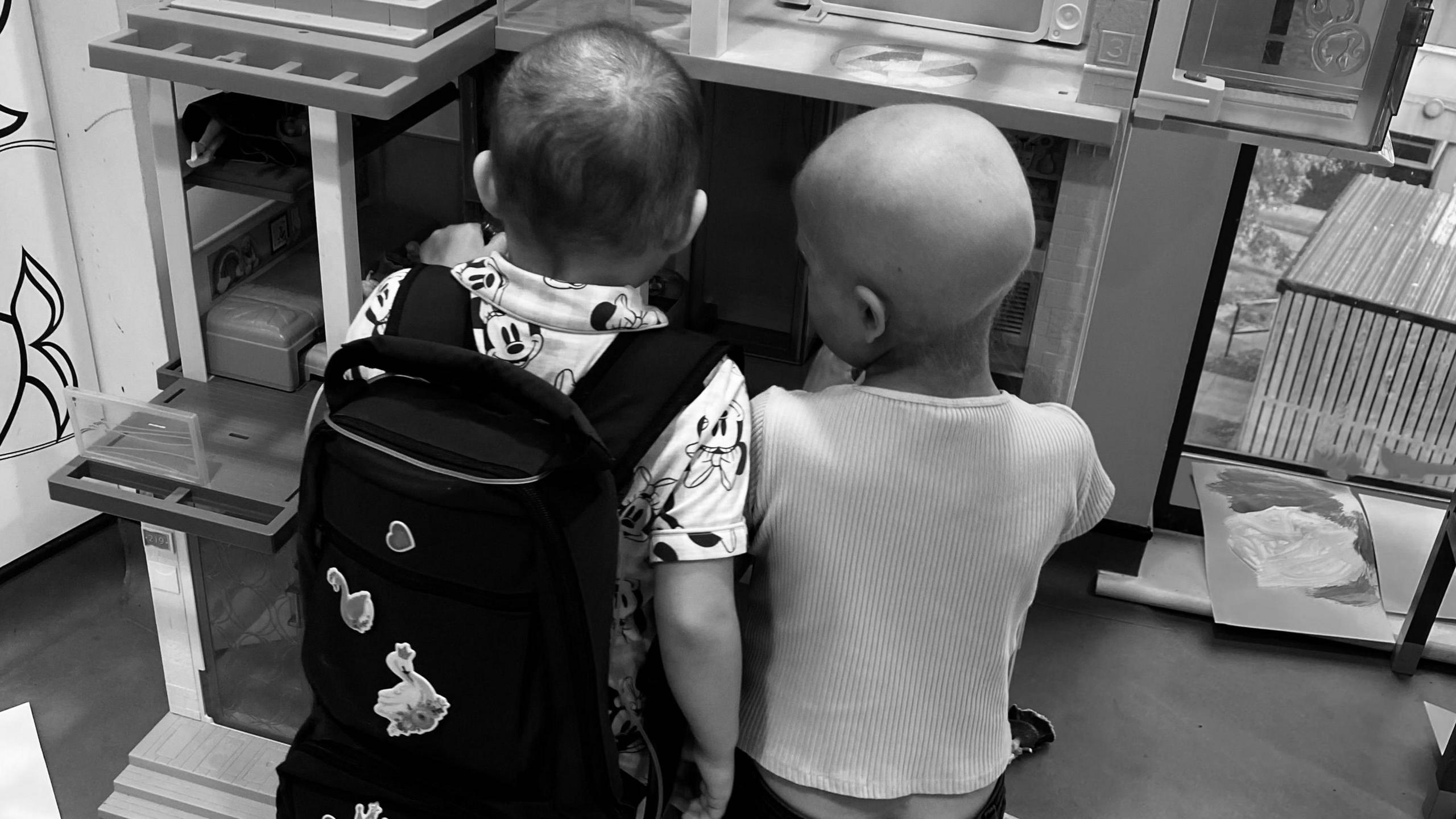 Girls' backs to camera. Lacie is wearing her backpack, Betsy has lost her hair.  