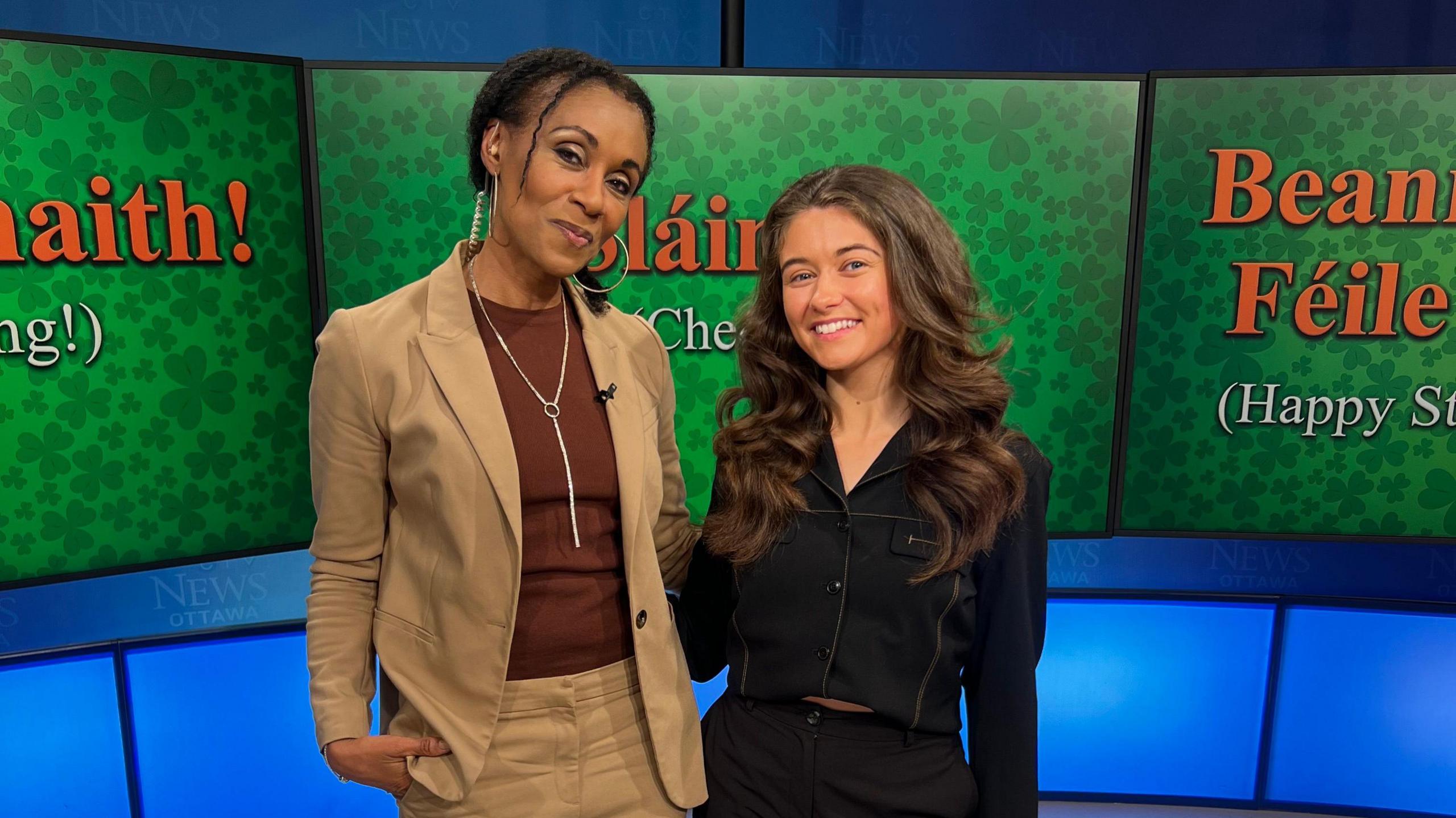 Clíodhna Ní Chorráin stands on the right beside Rosey Ugo Edeh, CTV Morning Live News anchor, in the CTV studio. There are green graphics with Irish phrases in the background.