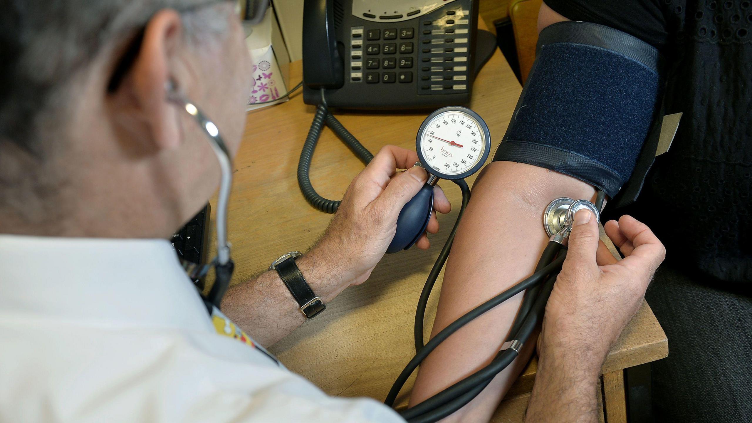 A doctor measuring a patient's blood pressure on their arm