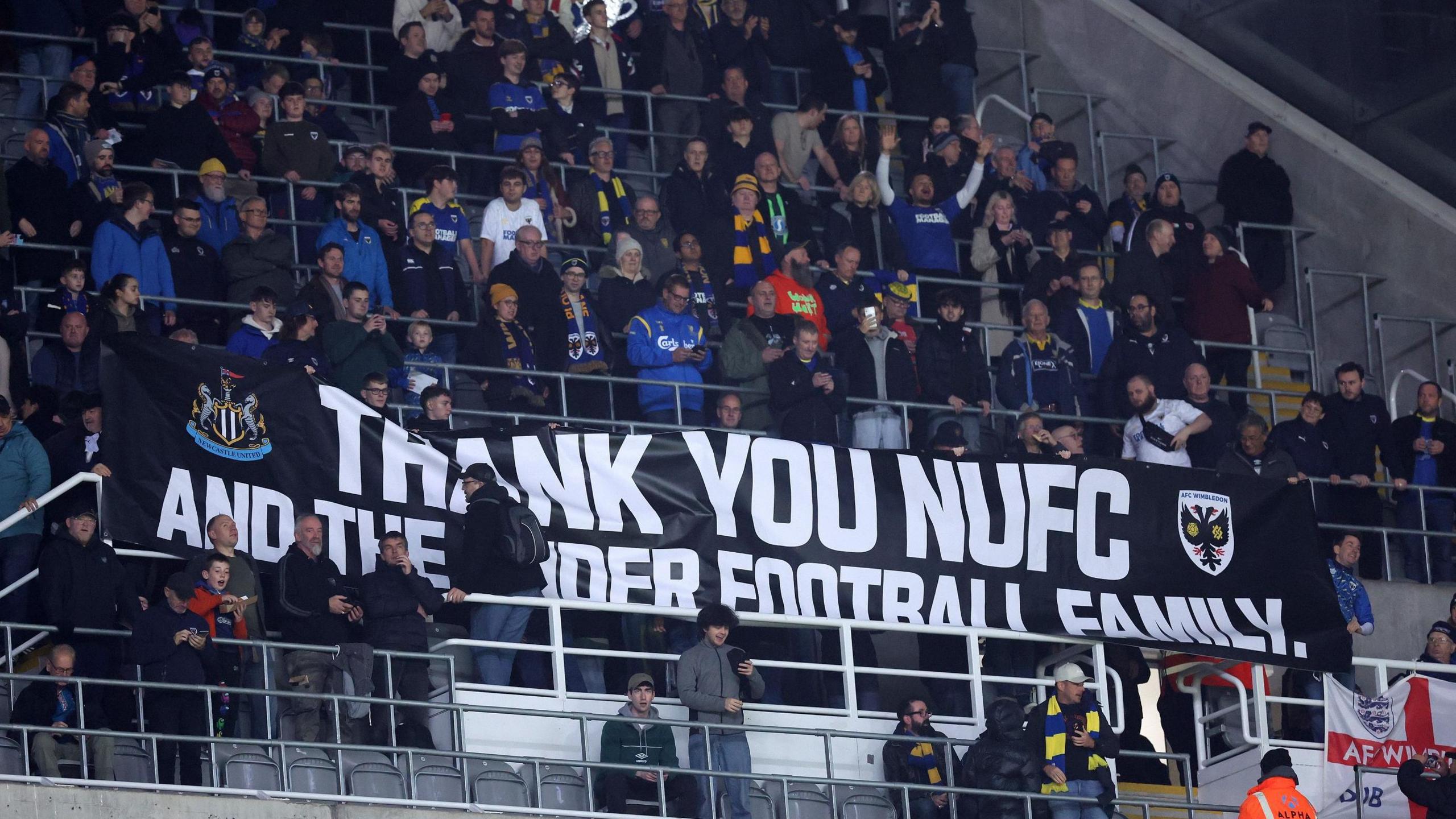 AFC Wimbledon's fans hold up a flag thanking Newcastle