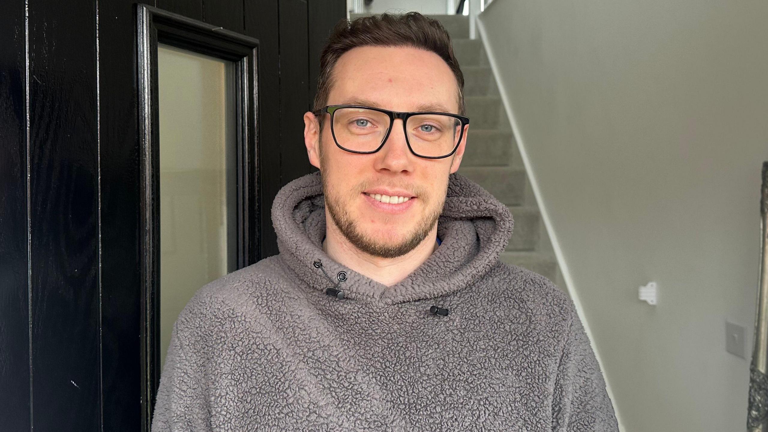 A man standing at the front door of a new build home