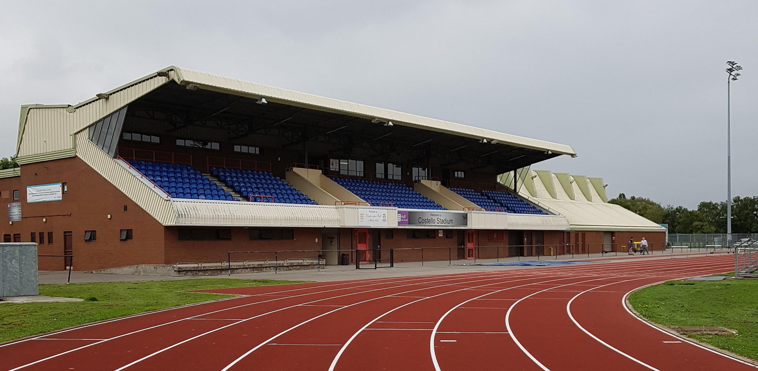 Shot of the stadium's running track with a stand for seating in the background. The red-coloured track has eight lanes denoted by white lines.