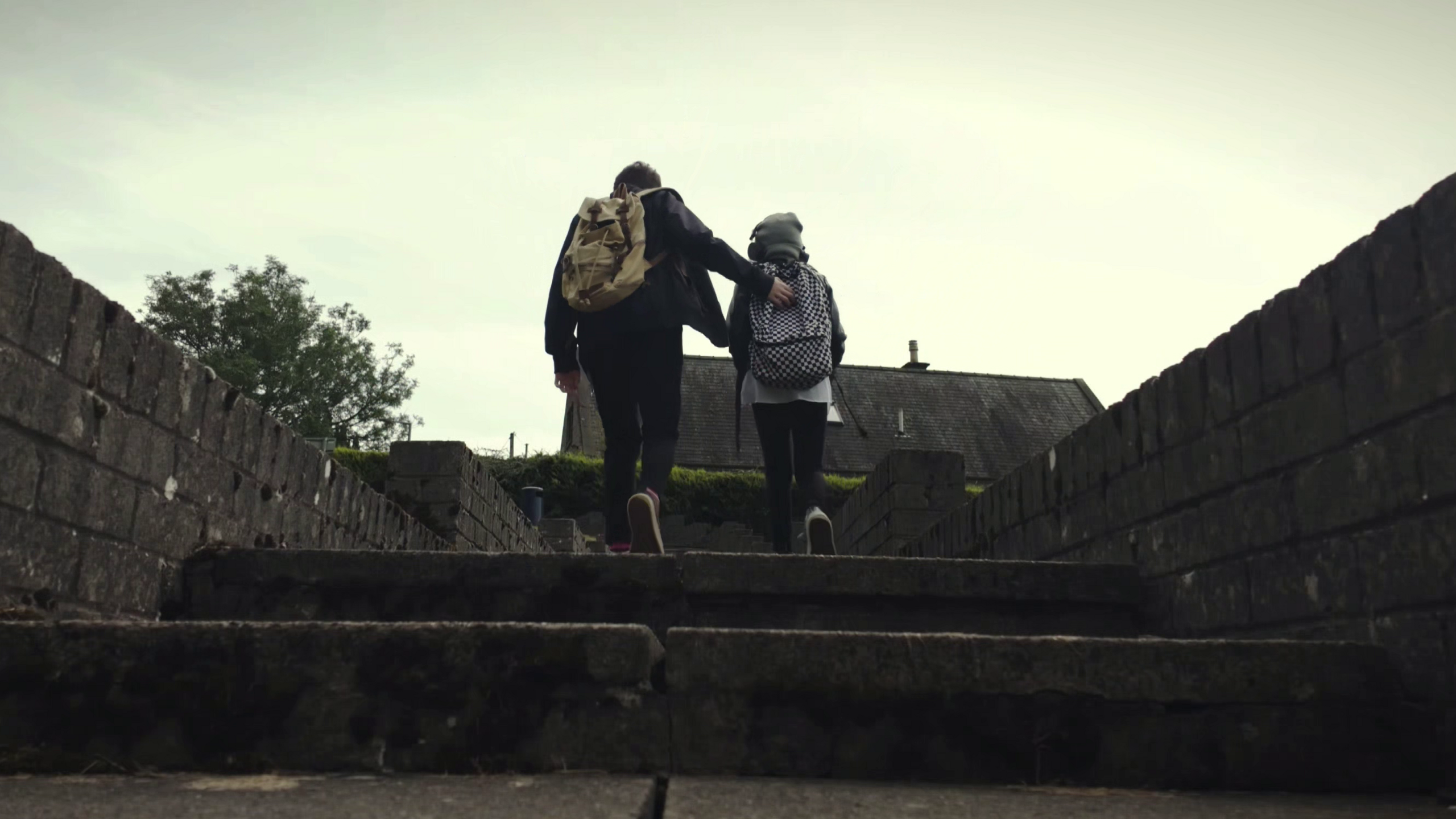 Two young people with backpacks walk up a set of stairs