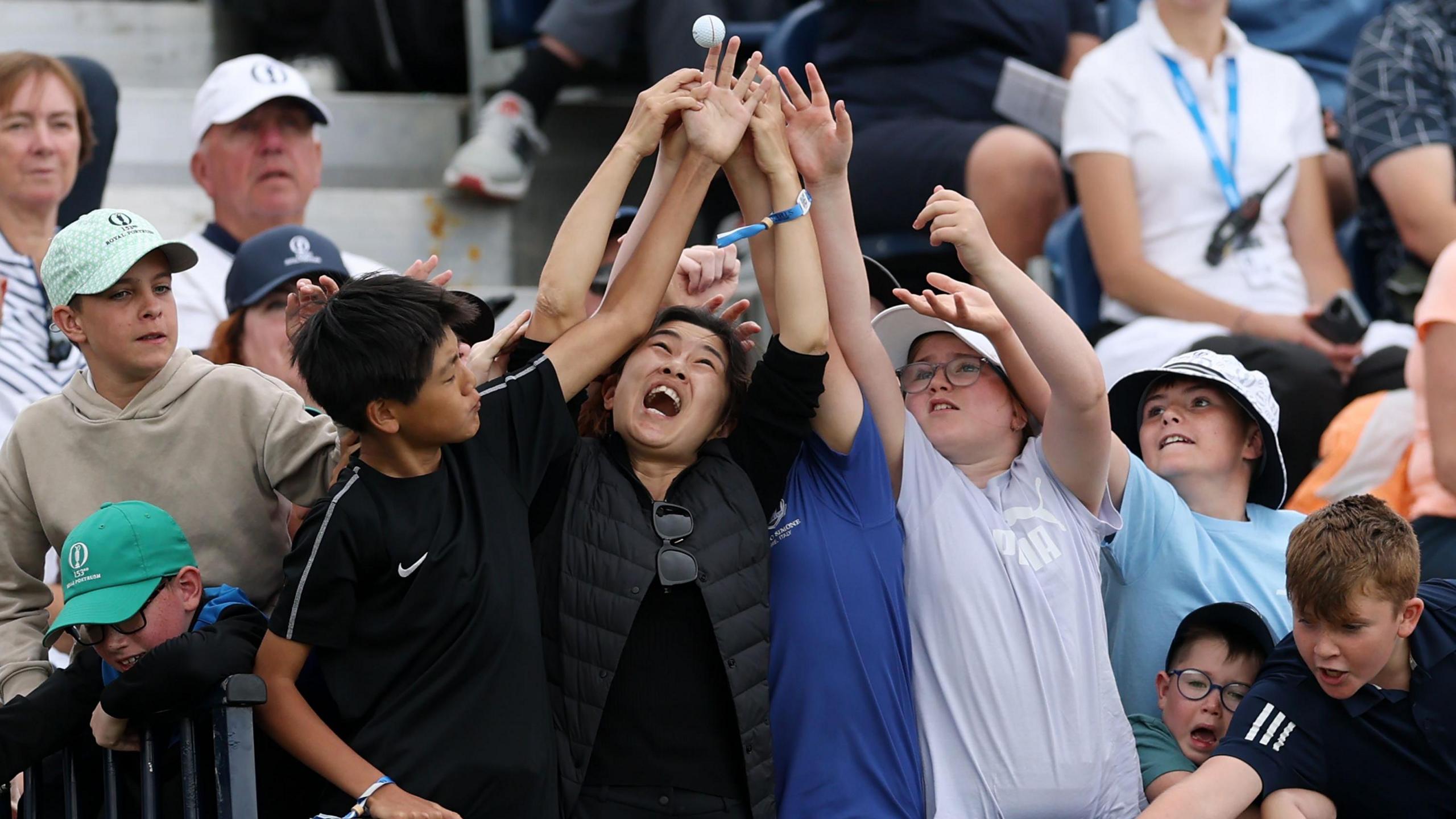 Young fans try to catch a golf ball