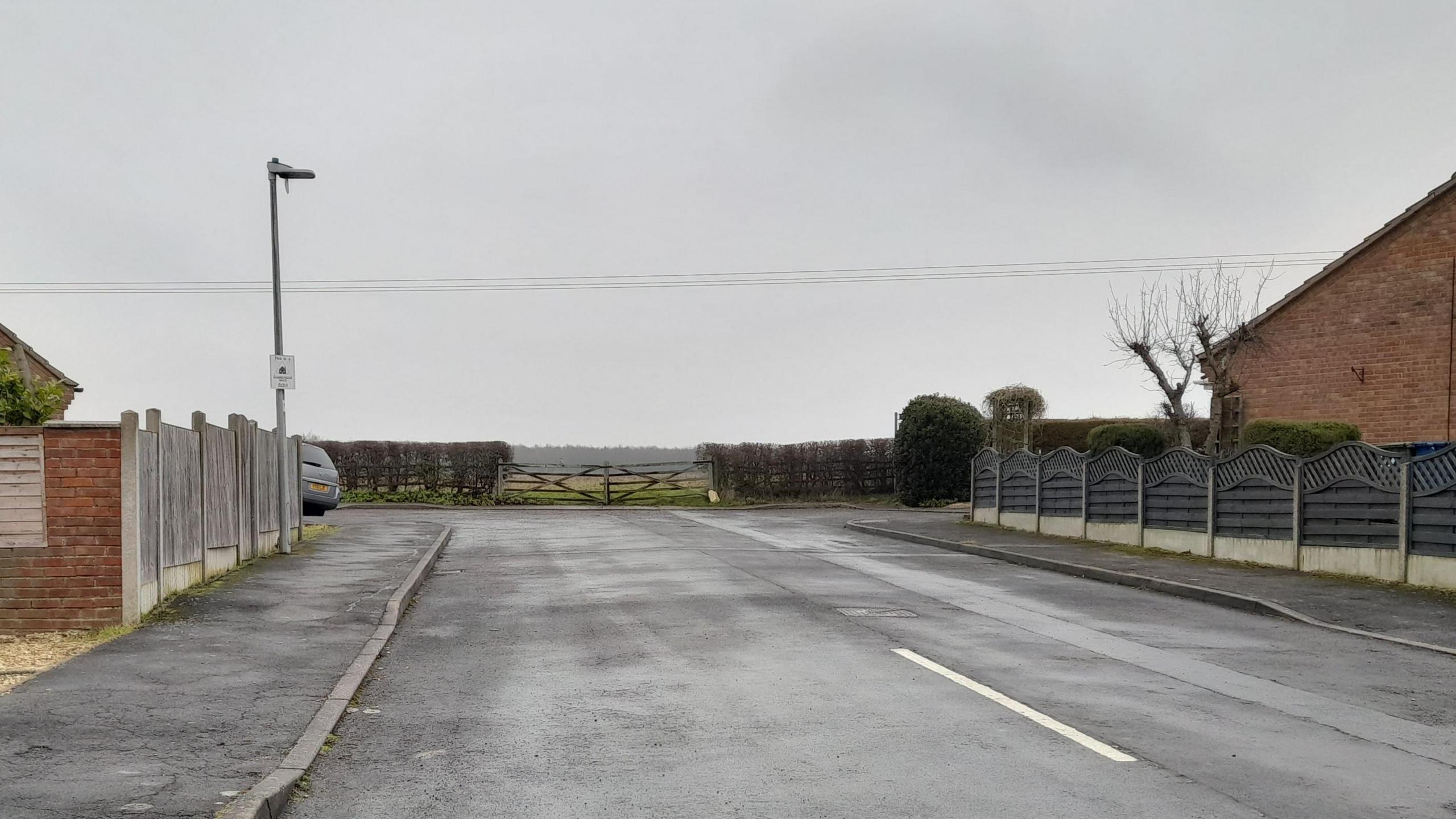 Corn Close in Fiskerton. The picture shows a cul-de-sac. There is a wooden gate at the end of the road which will be the access to the site. 