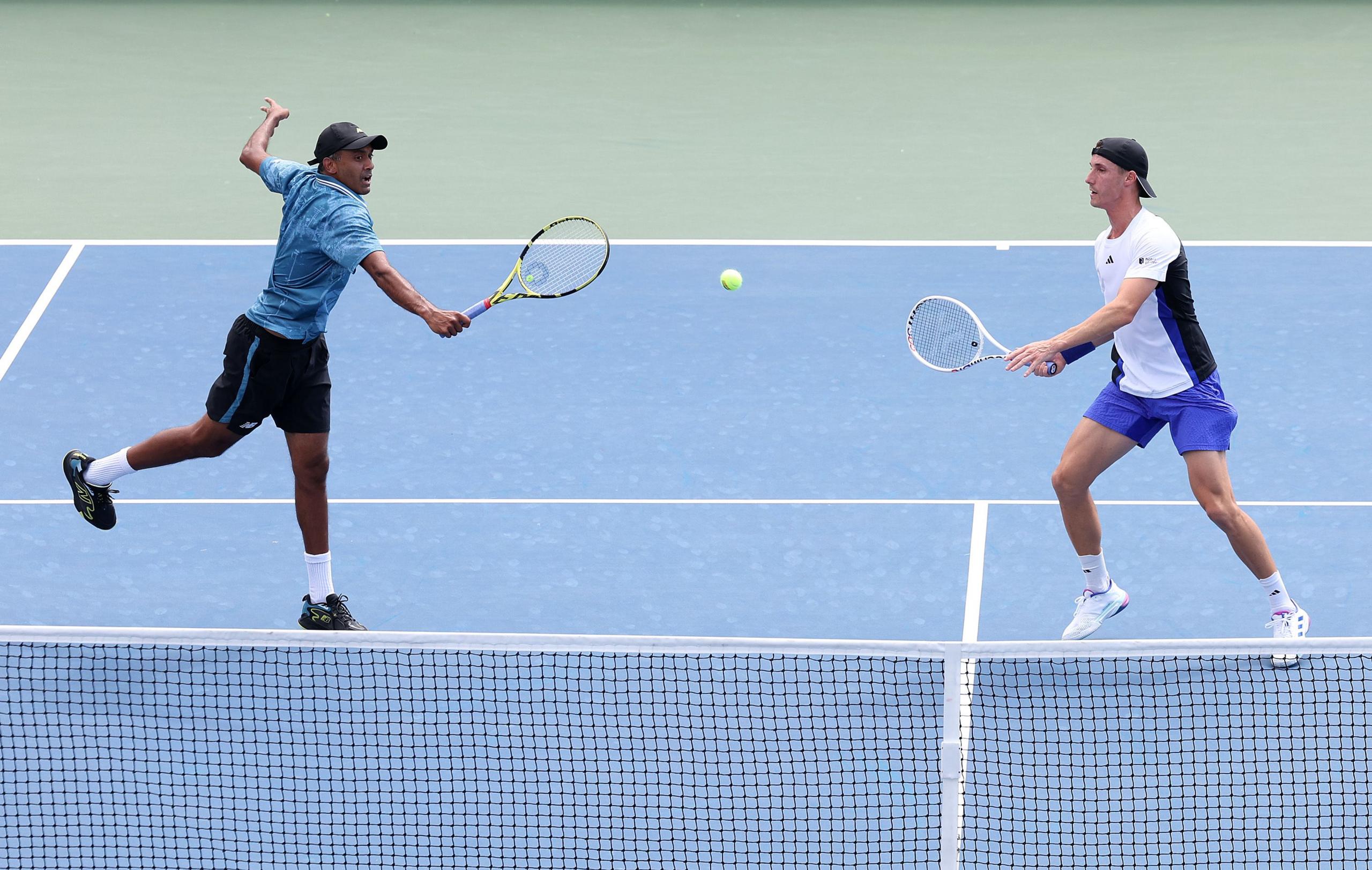 Rajeev Ram and Joe Salisbury move towards a ball which is flying between them as they stand at the net