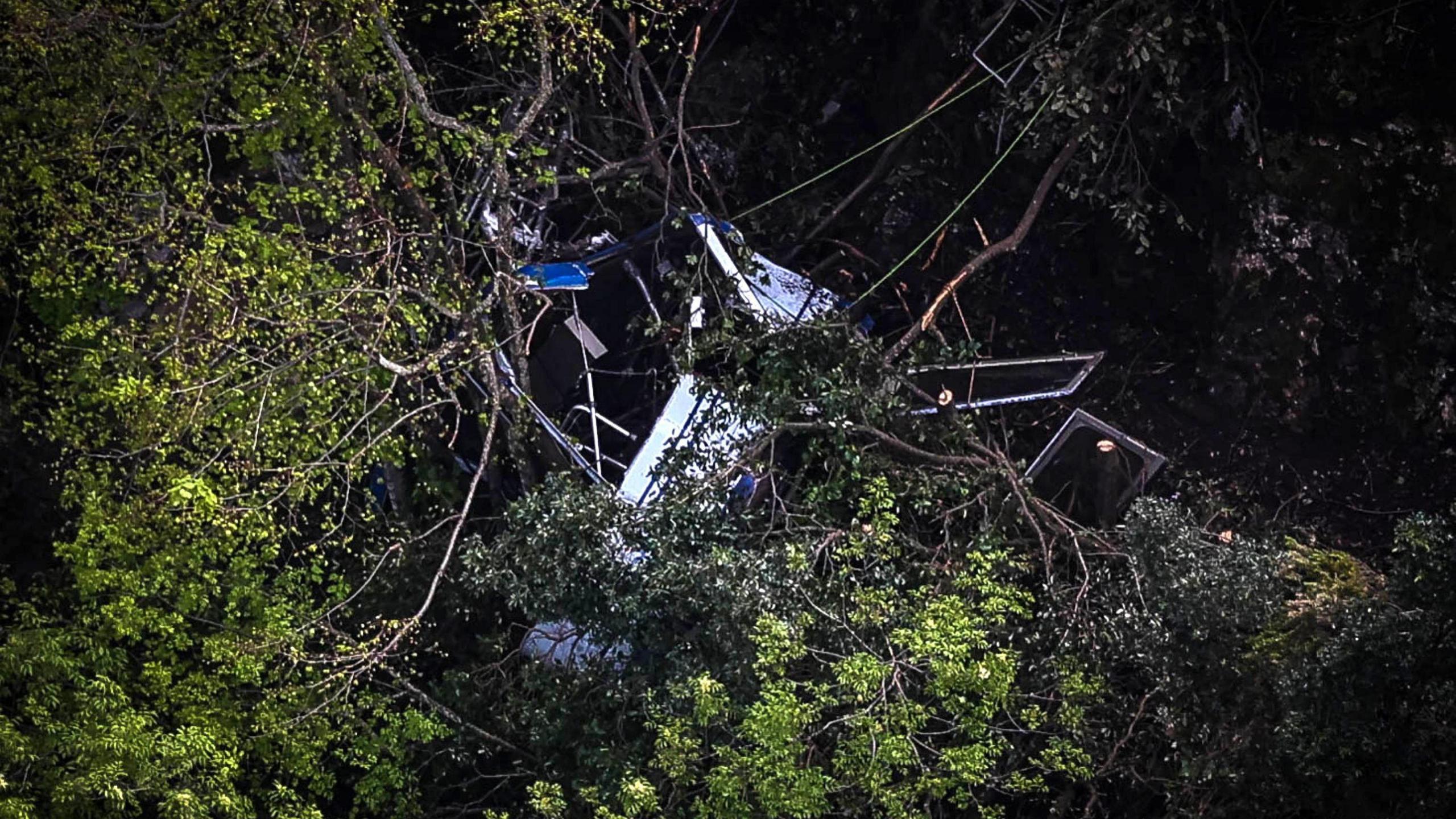 An image of the wreckage of a cable car in thick woodland after at crashed.