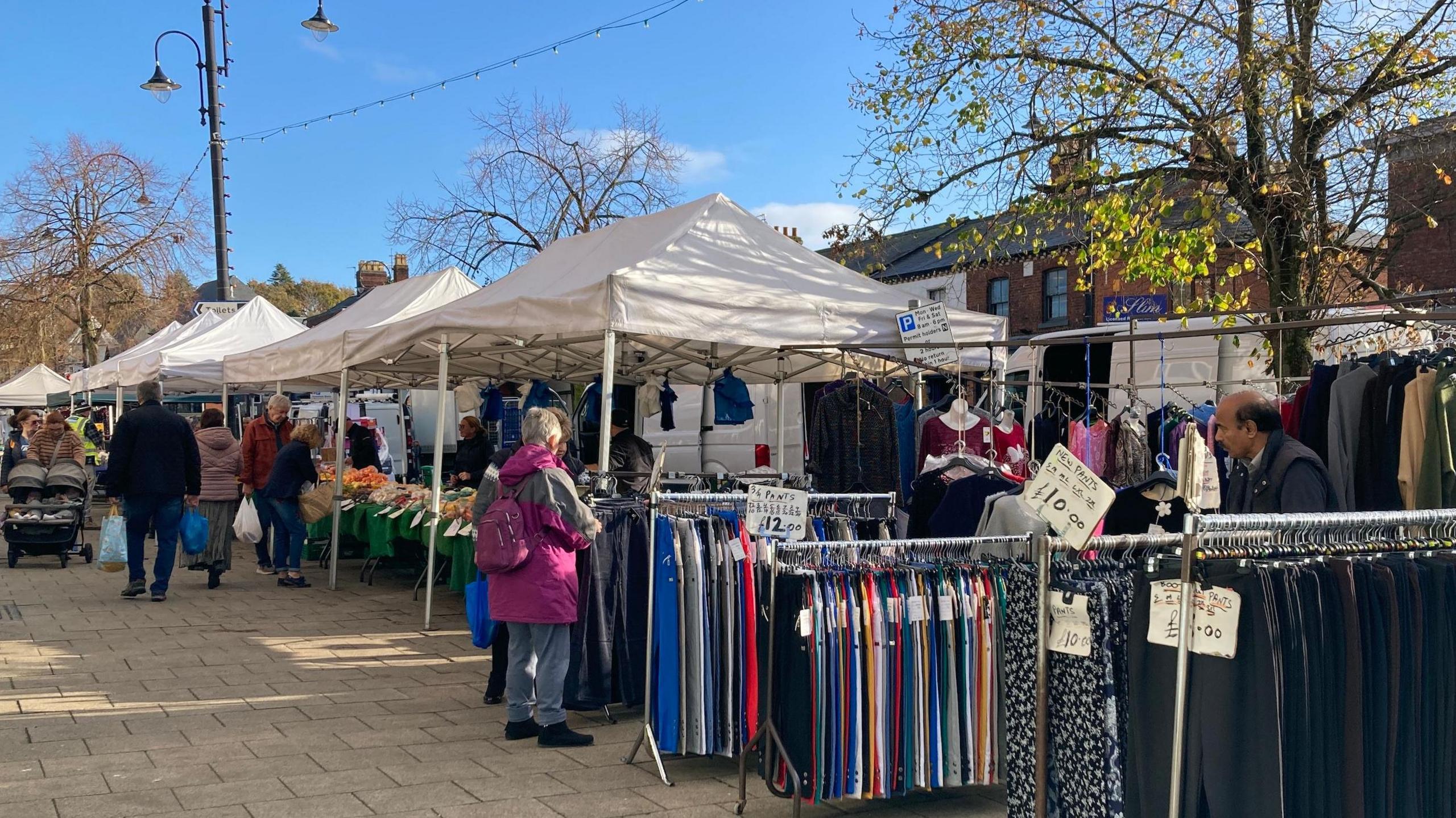 View of a clothing stall next to a vegetable stall at Frodsham Market