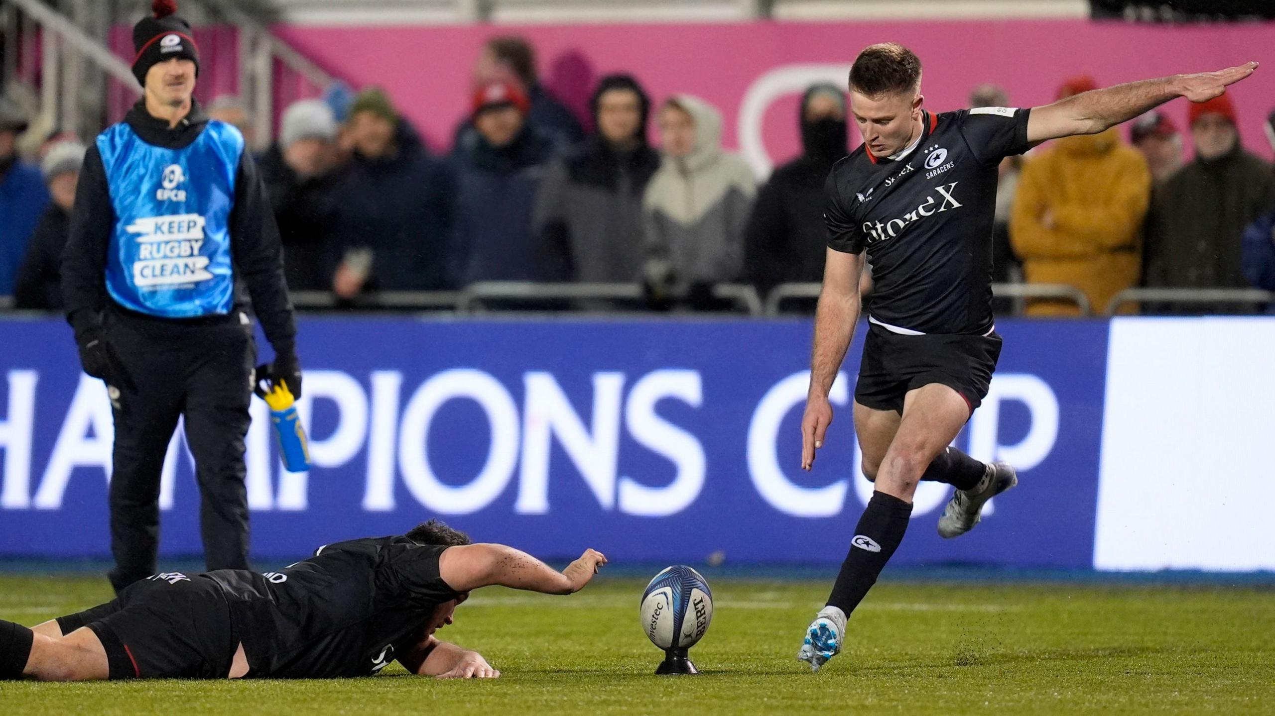 Jamie George stops the ball from blowing off the tee as Fergus Burke kicks a conversion