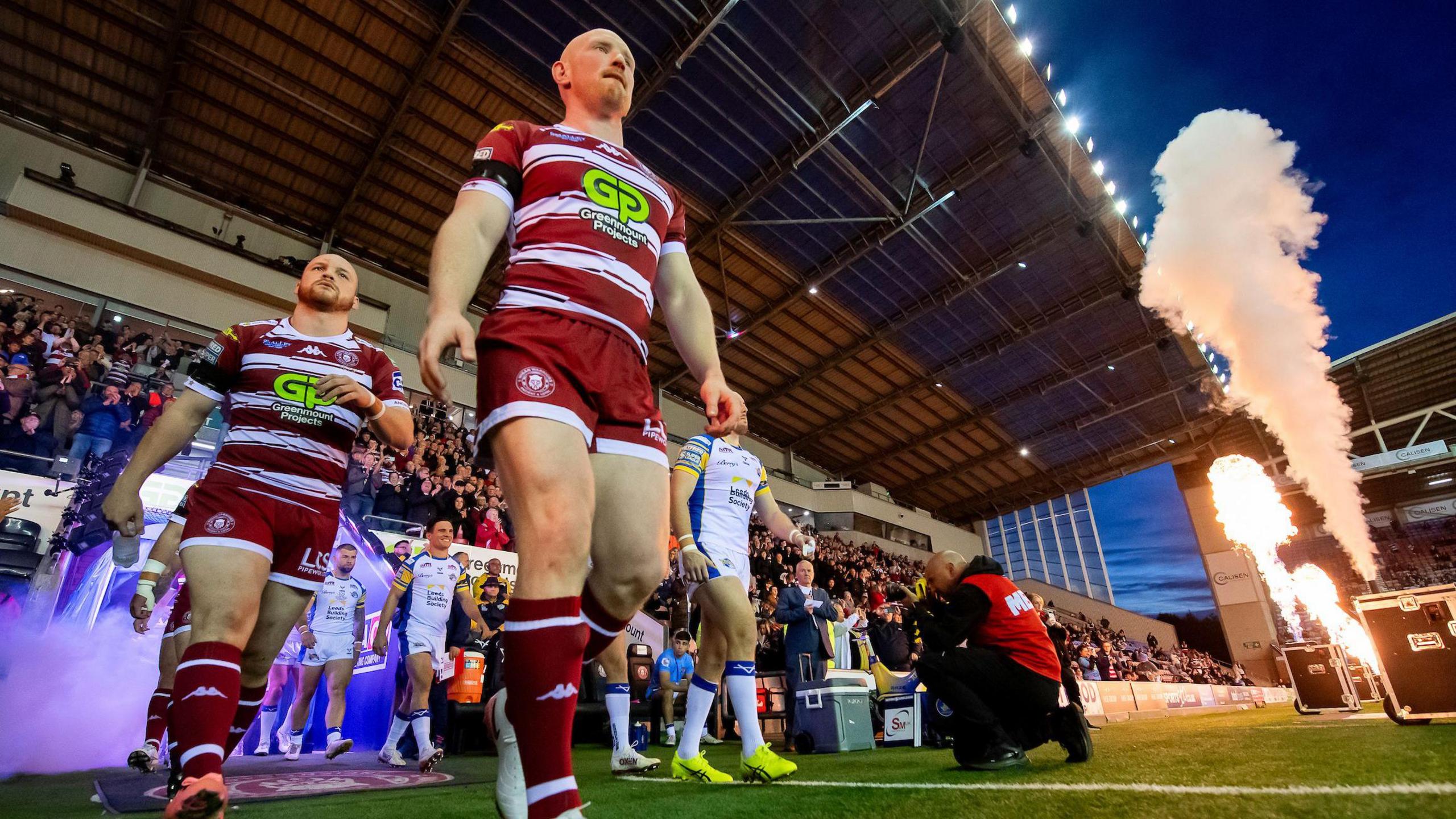 Liam Farrell leads Wigan out of the tunnel onto the pitch as pyrotechnic flames burst into life