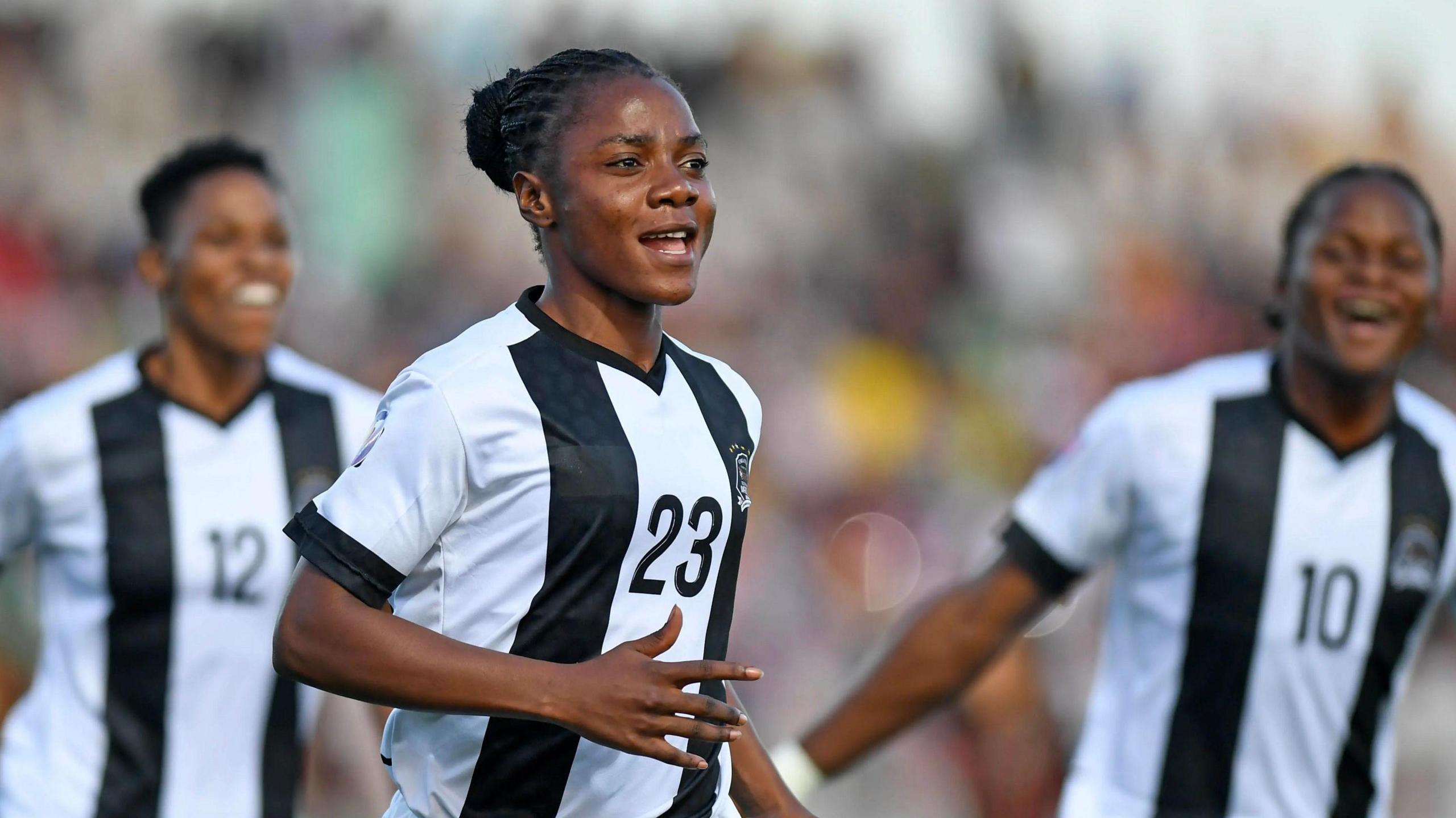 Marlene Kasaj, wearing a black and white shirt with the number 23 on the chest, has a smile of her face as she runs away to celebrate a goal