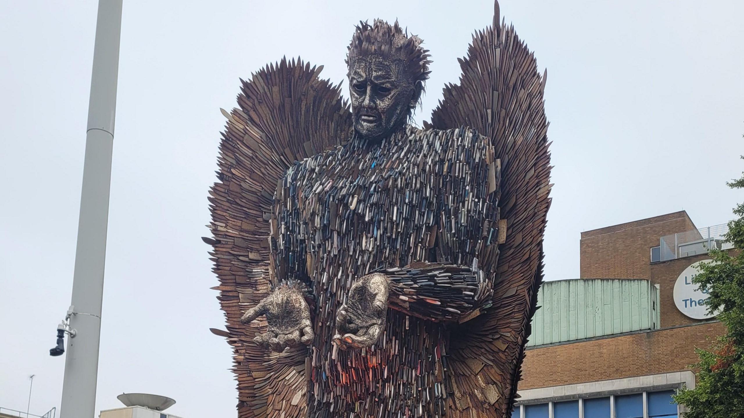 A Knife Angel statue in the centre of Luton, made up for 100,000 blades, with the angel holding its hands out 