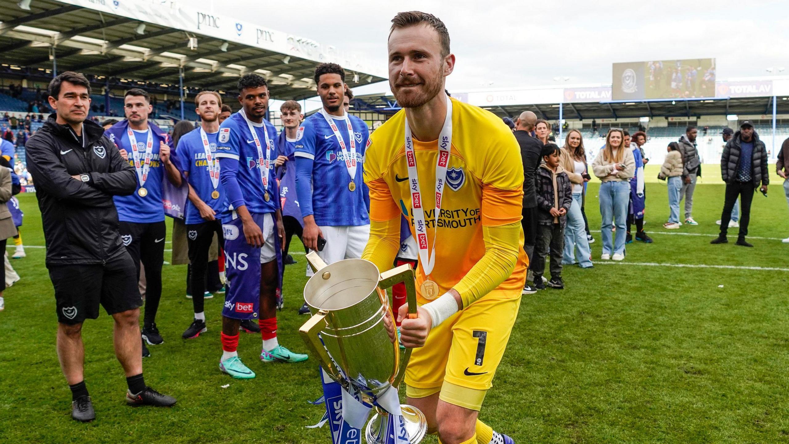 Portsmouth goalkeeper Will Norris gets hold of the League One winners trophy at Fratton Park