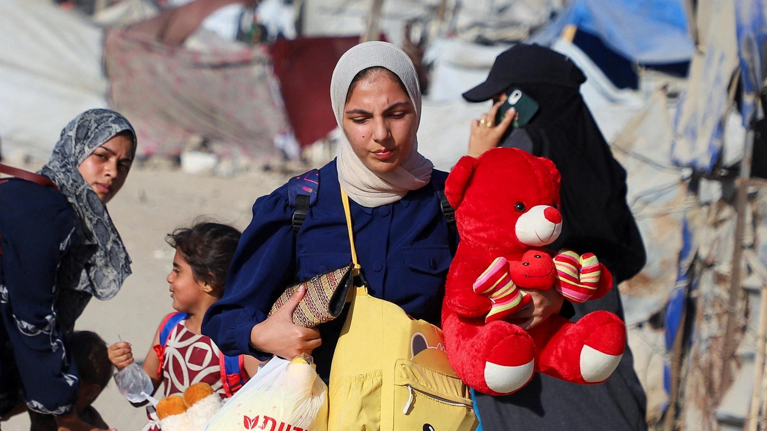Palestinian women walk with their belongings, including children's toys, as they flee an Israeli military operation in Gaza City.