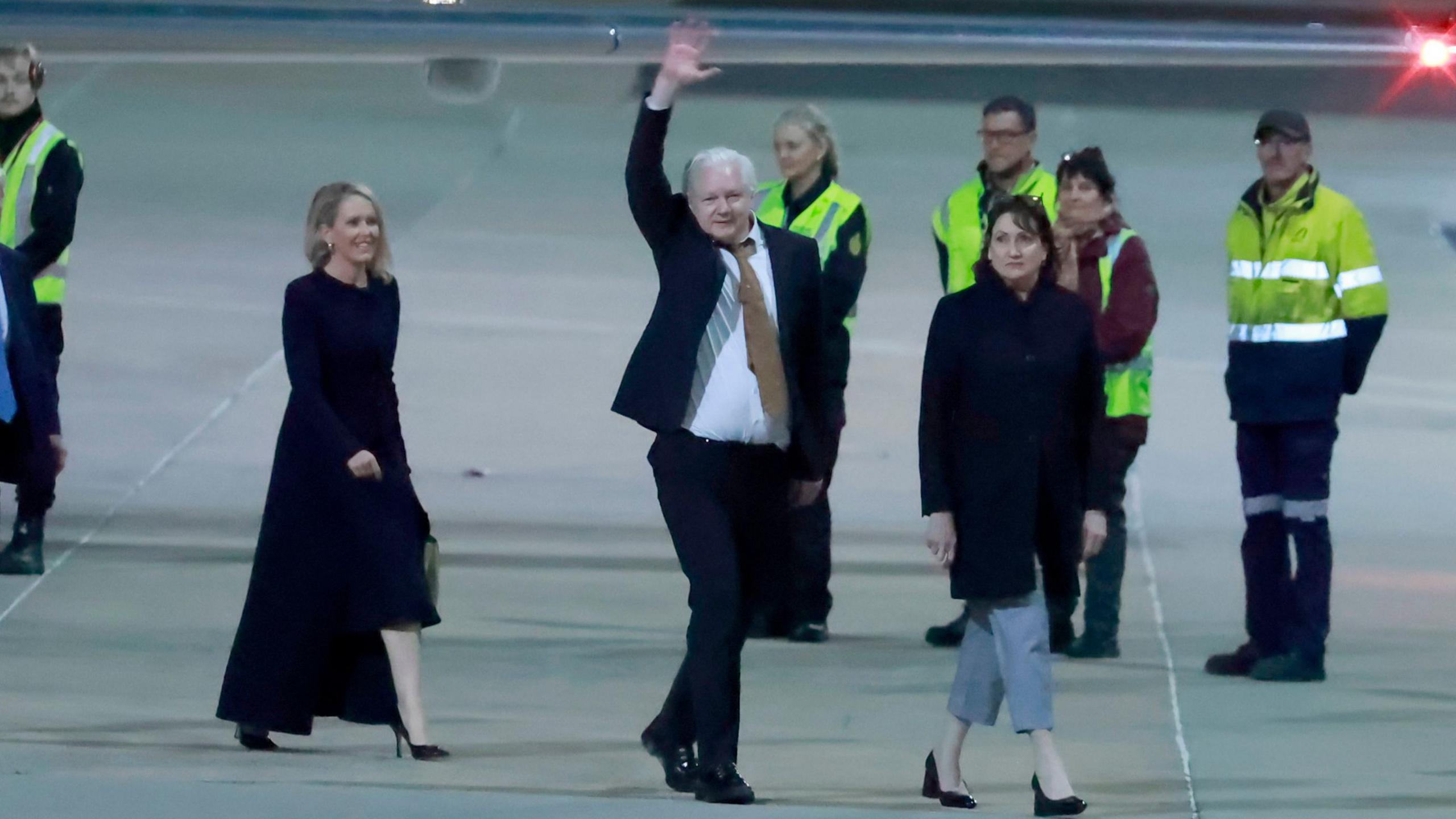 Julian Assange waving at airport as he arrives in Australia