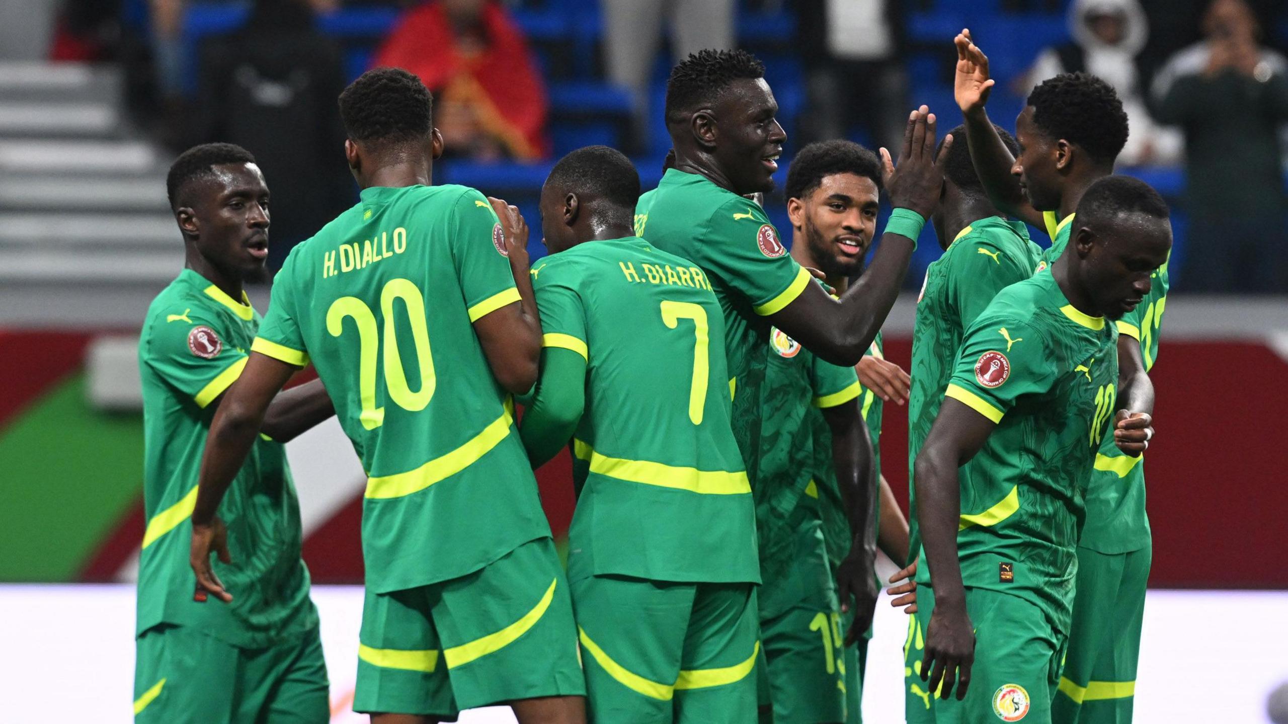 Senegal players, dressed in an all-green kit, celebrate a goal