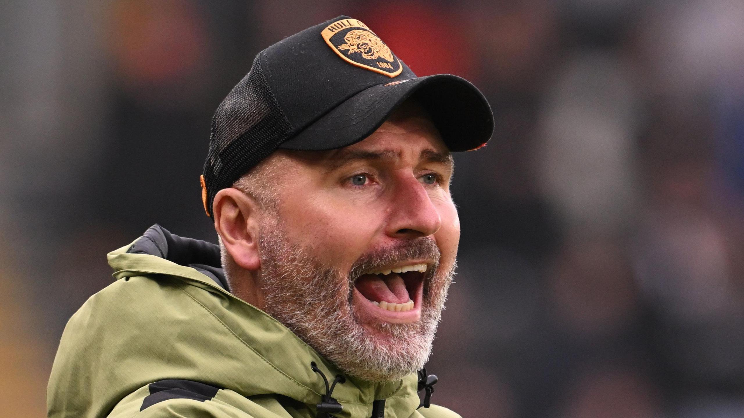 Tim Walter, wearing a baseball cap, watches Hull play West Brom in November