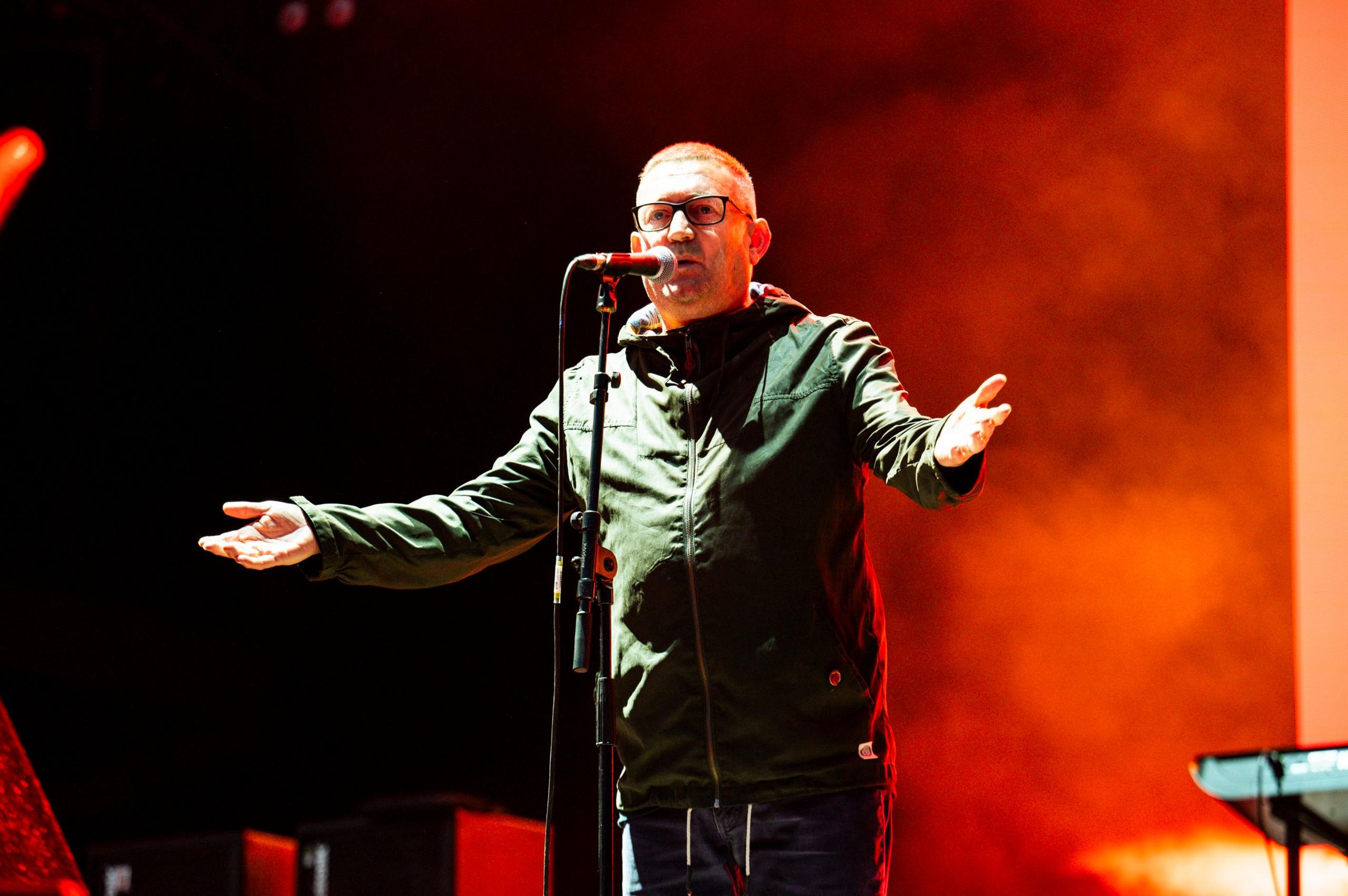 Paul Heaton standing, arms outstretched, in front of a microphone at Kendal Calling in 2024