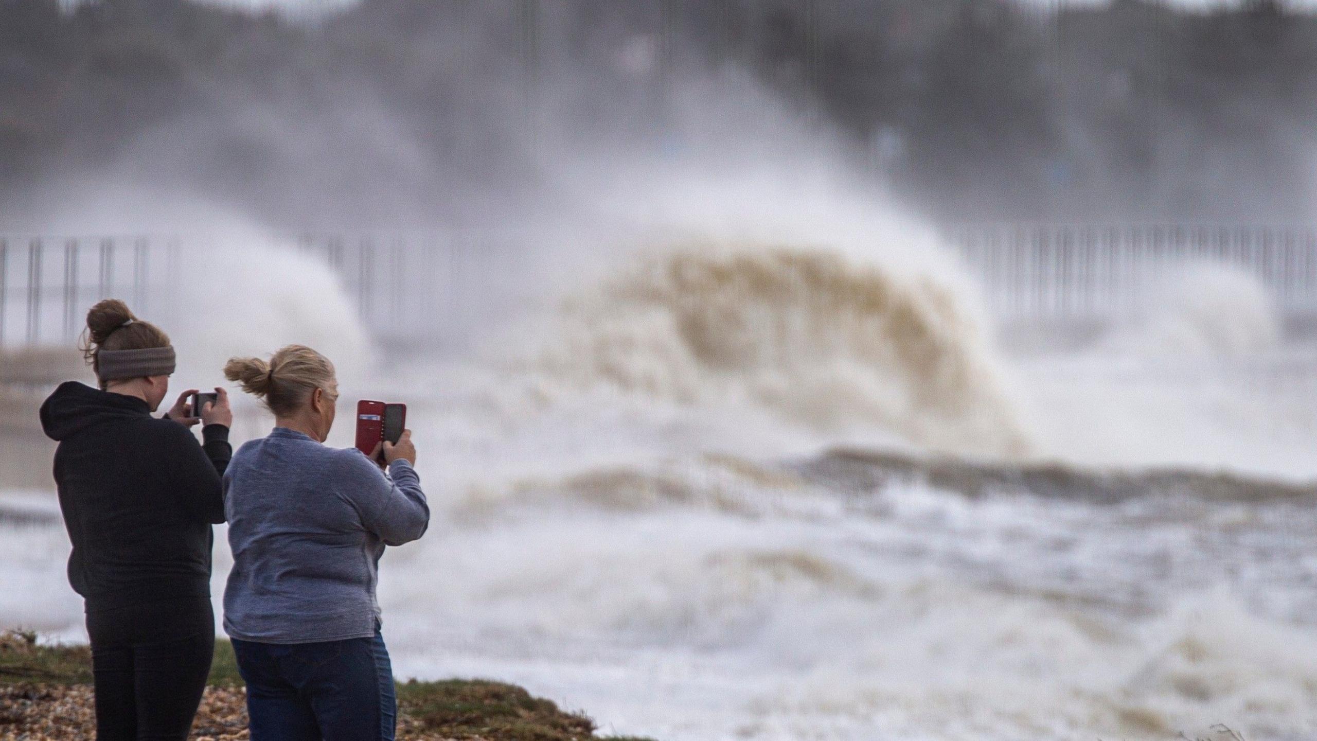 Two women take pictures of a storm sea