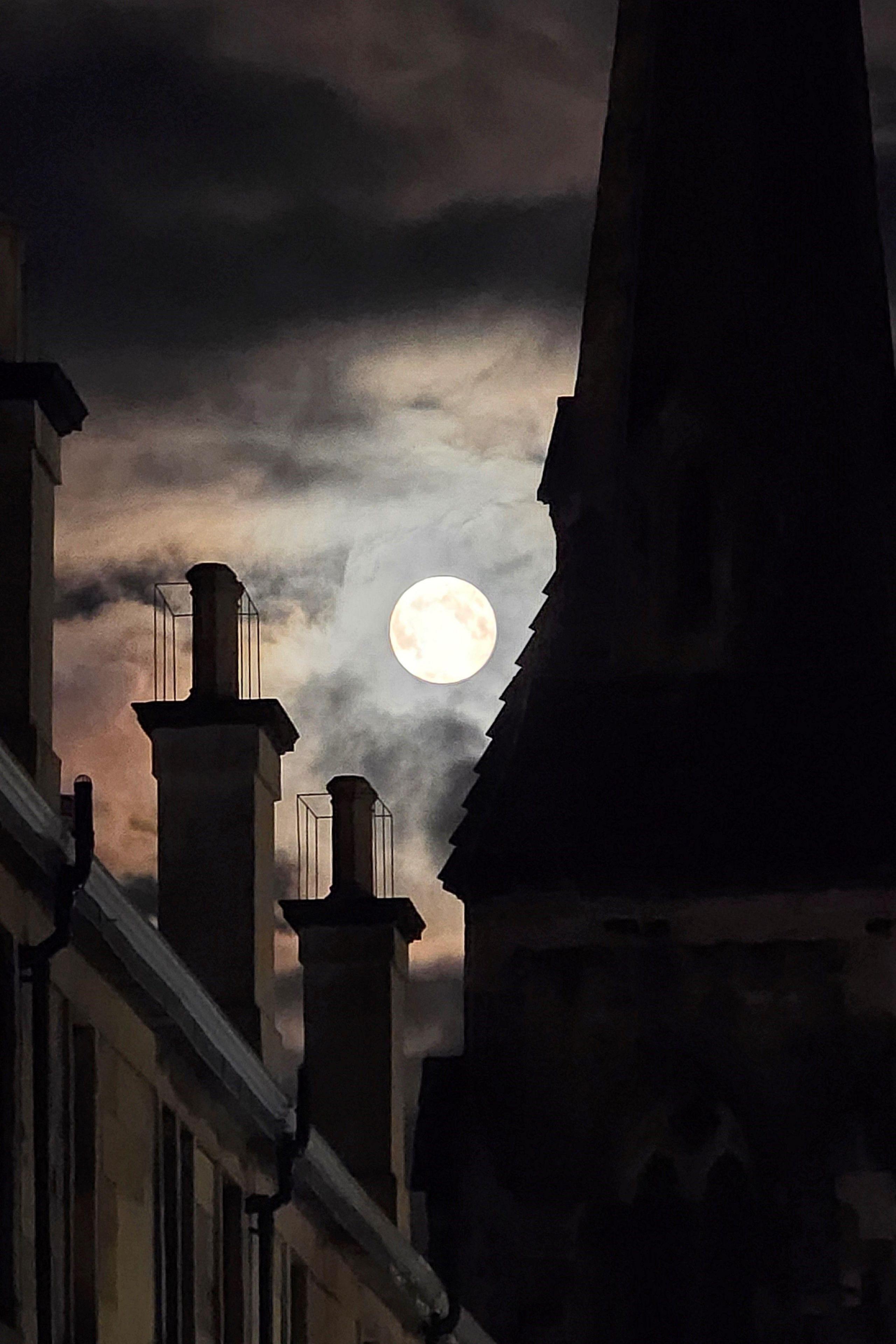 The moon lights up a crack in the sky between buildings giving the chimney tops a wonderful atmospheric feel.