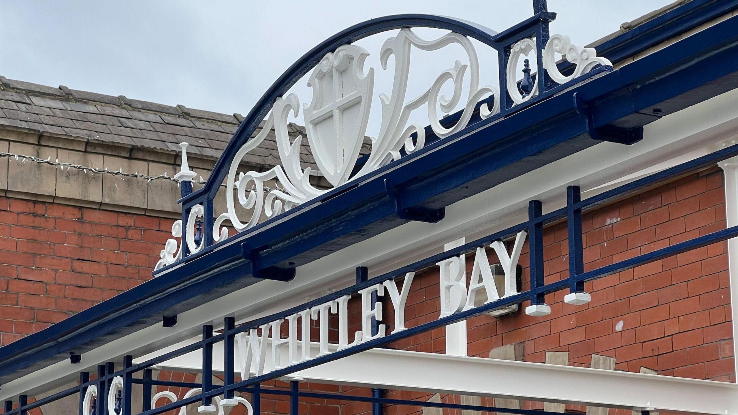 Newly painted Whitley Bay sign at the front of the station below a decorate archway. 