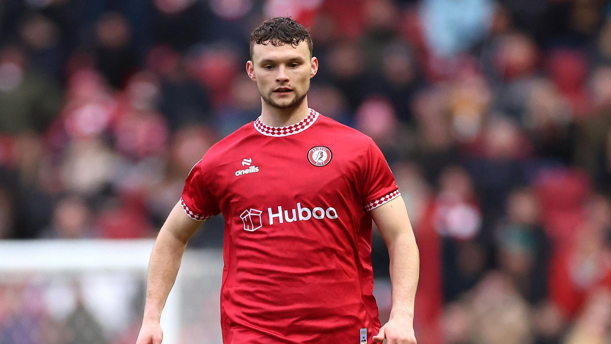 A photo of Luke McNally playing for Bristol City in their red home kit during a match against Derby County in January 2025