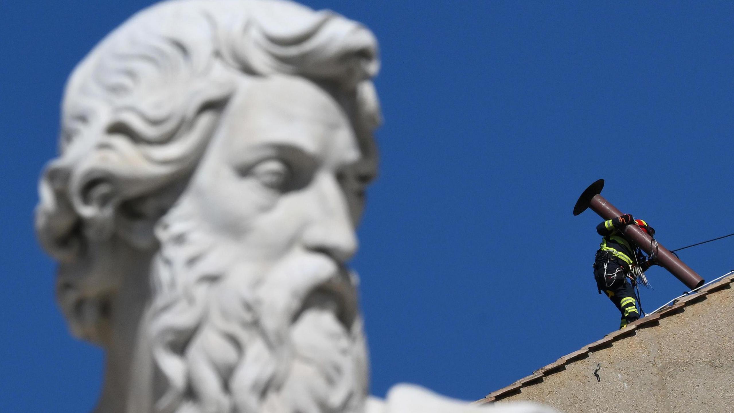 Image shows fire service worker fitting a chimney to the top of the Sistine Chapel ahead of the conclave 