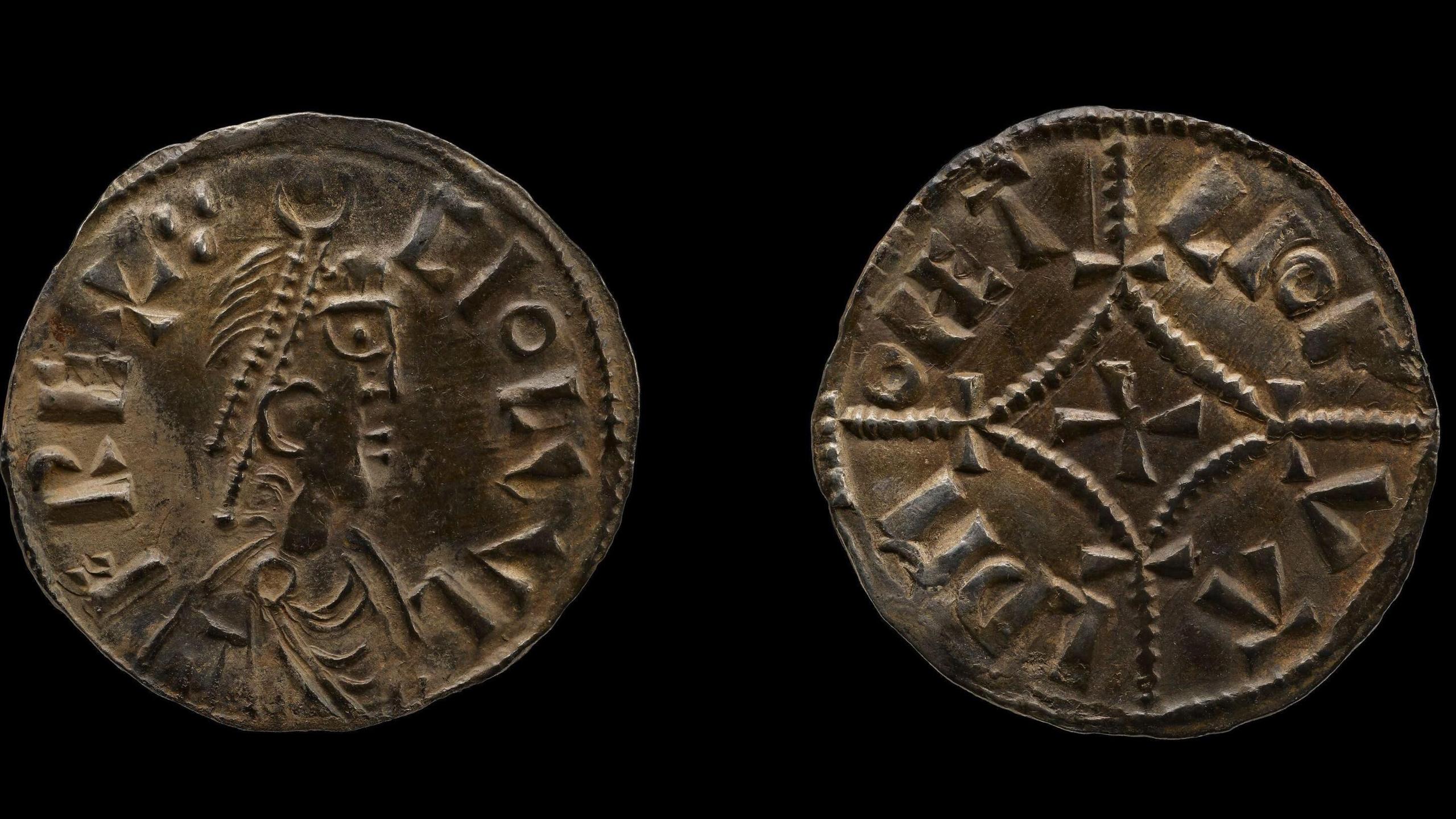 Two golden Viking coins against a black background. They coins have the profile of a Viking's face and are bordered by Norse letters.