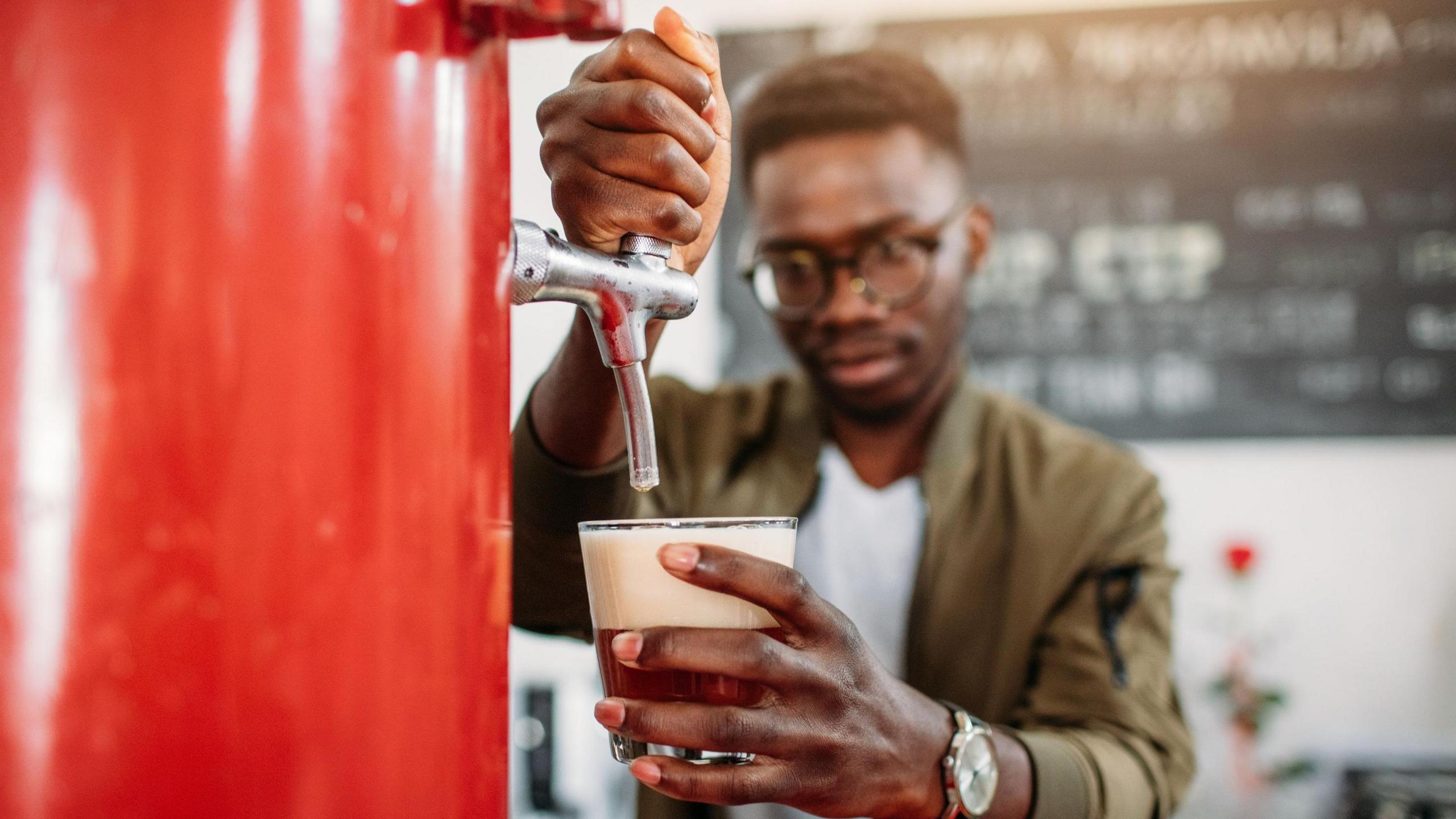 A man pouring a glass of beer from a red keg