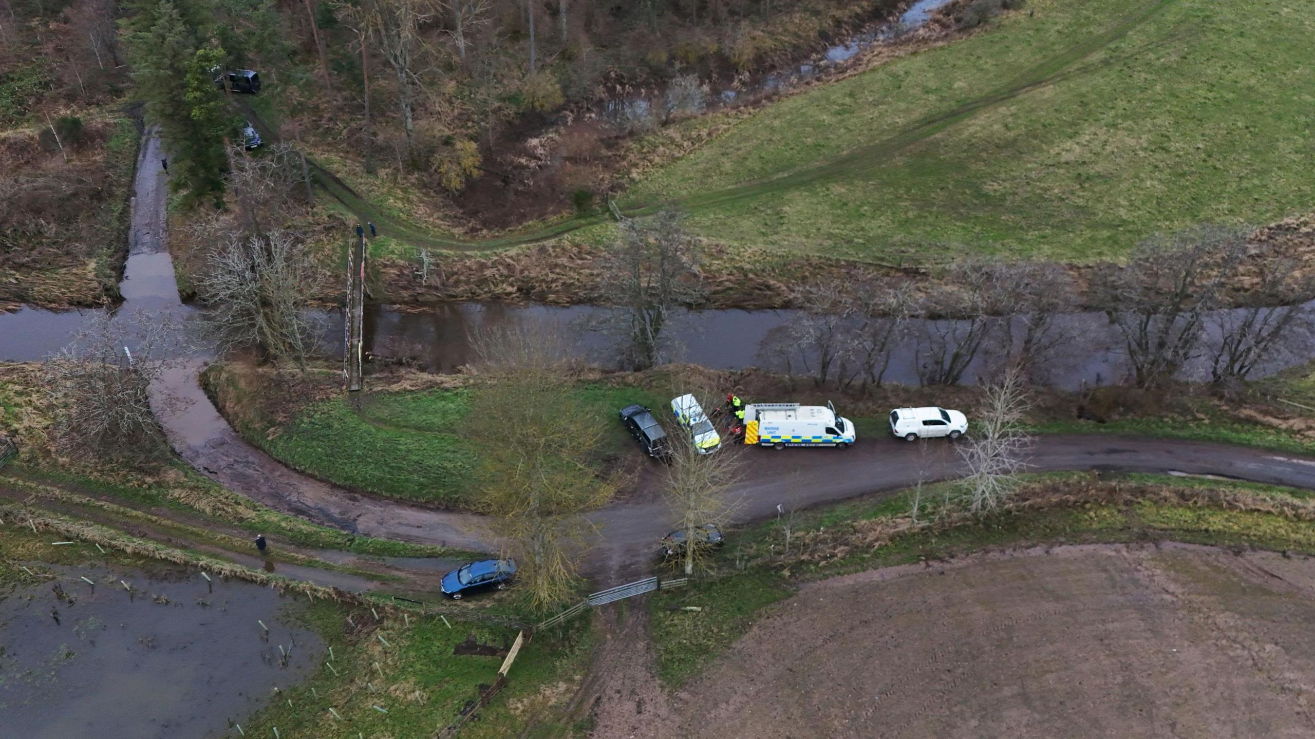 An aerial view of Abberwick Ford showing a rural road approaching a river with a number of emergency vehicles parked up.