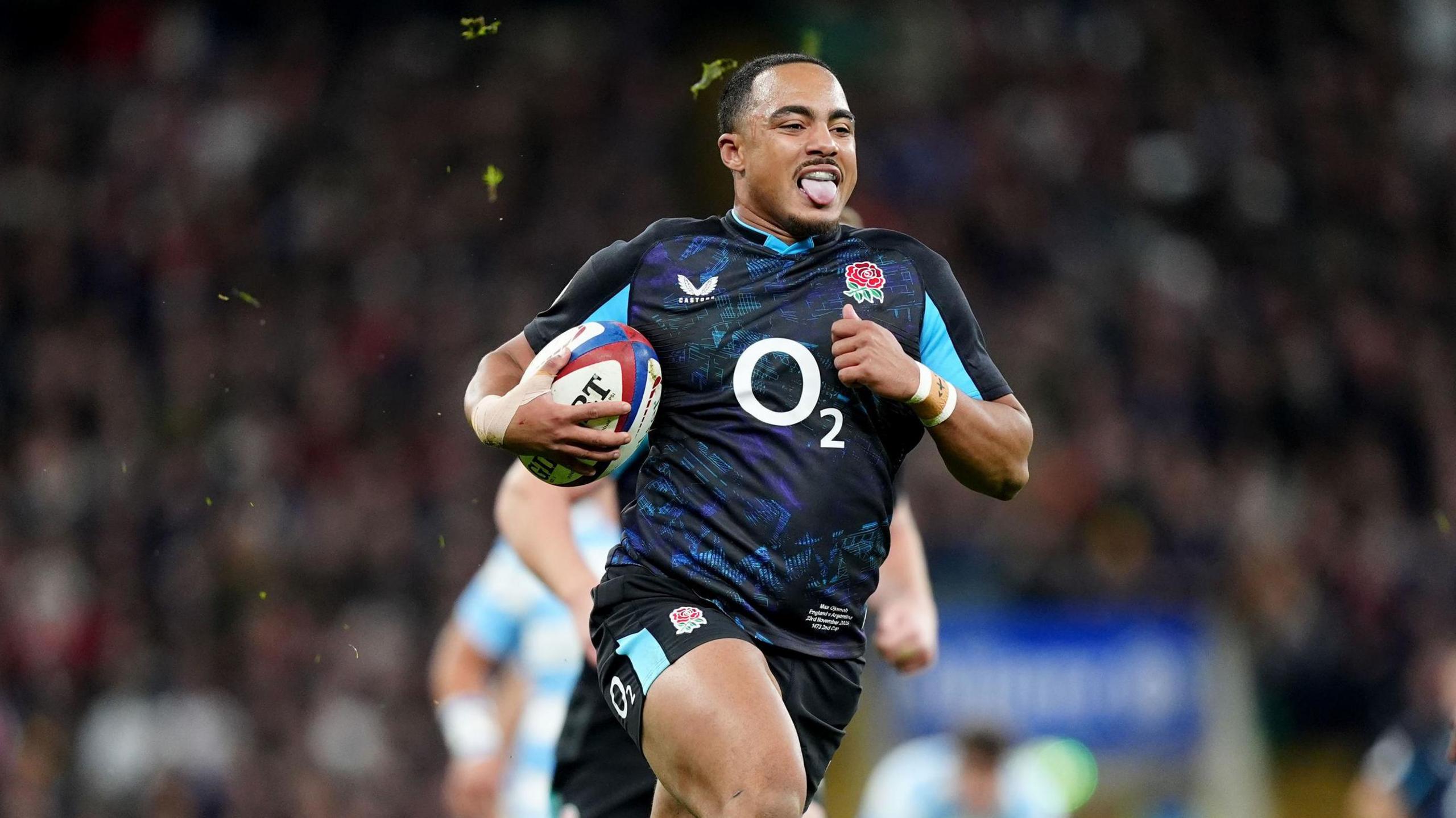 Max Ojomoh running with his tongue out as he scores a try for England 